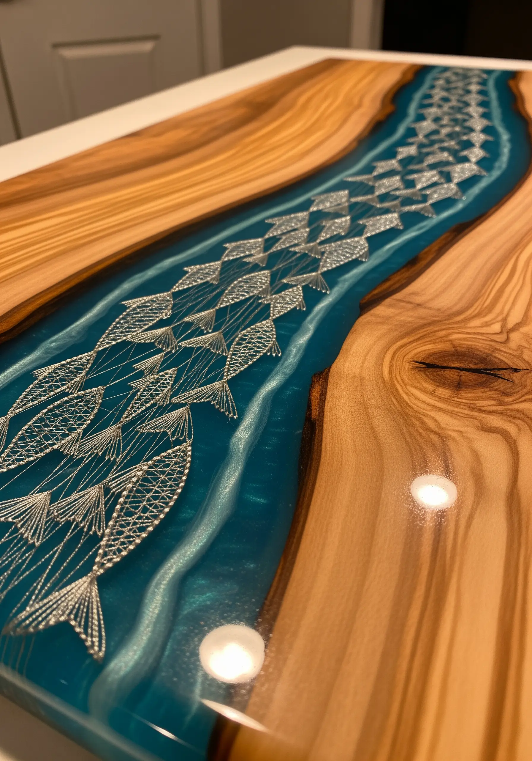 A wooden board with a blue resin river containing intricate white embroidered fish.