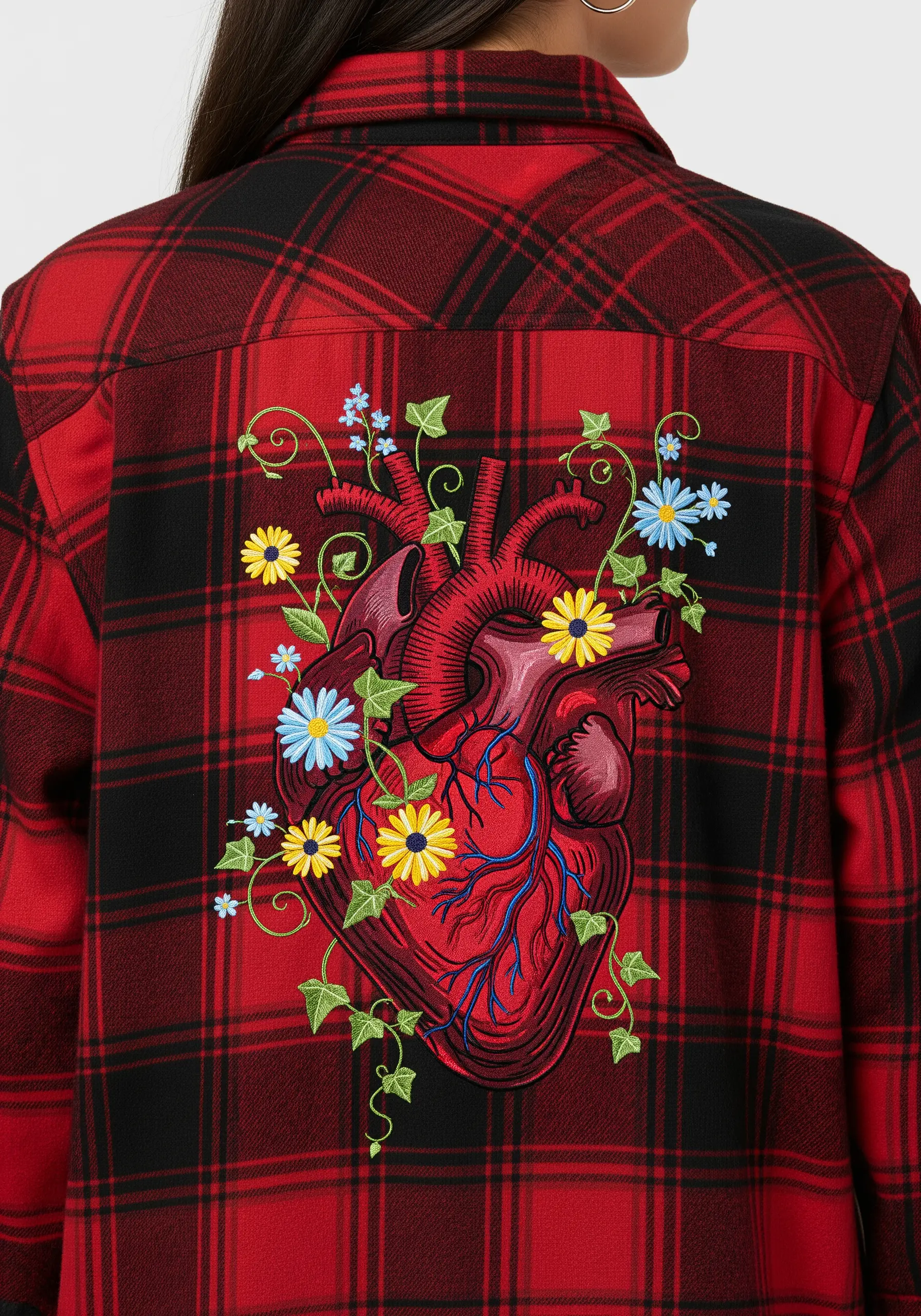 Embroidered anatomical heart with blue and yellow wildflowers on a red plaid shirt.