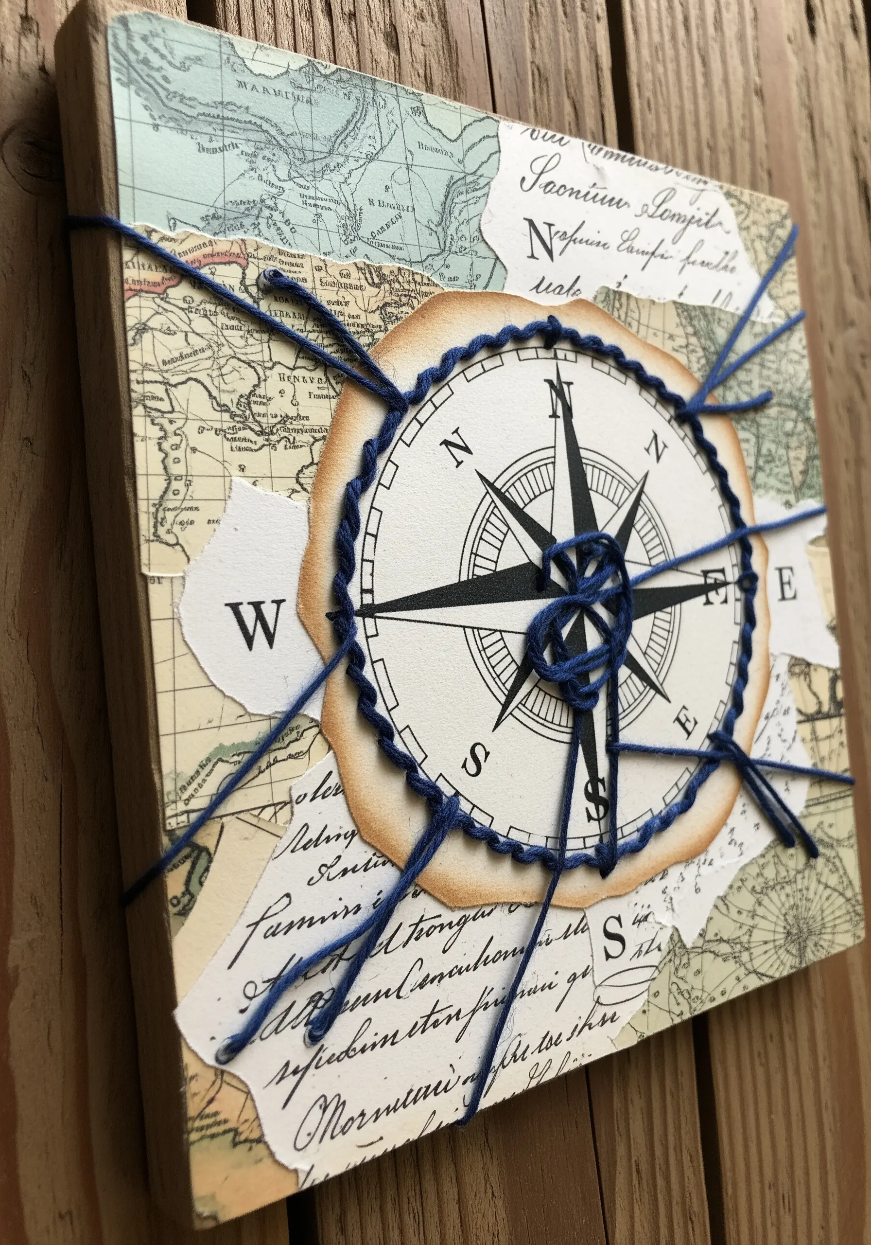 A paper compass collage framed with a thick blue blanket stitch and radiating threads.