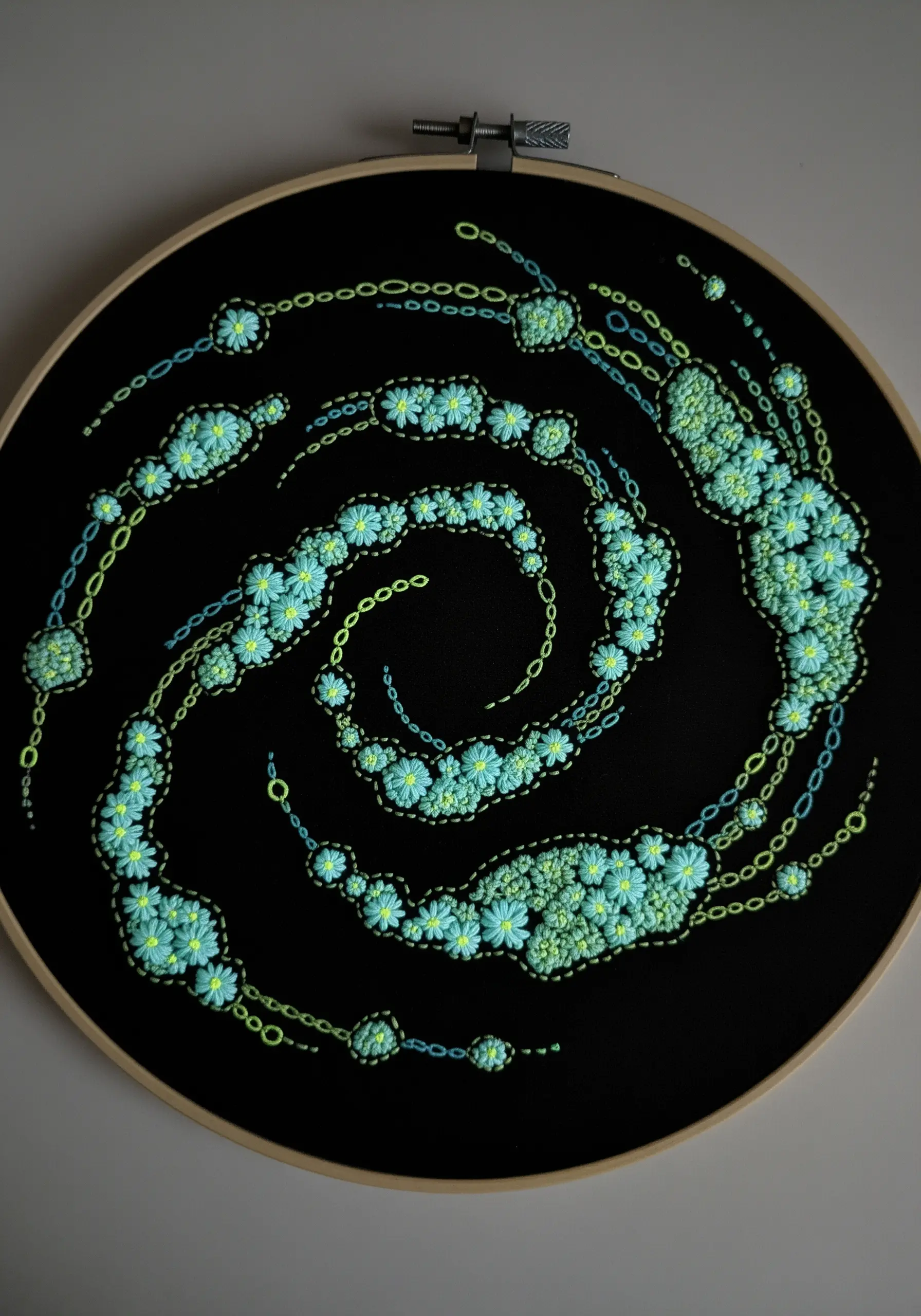 A swirling galaxy of flowers stitched with glow-in-the-dark thread on a black background.