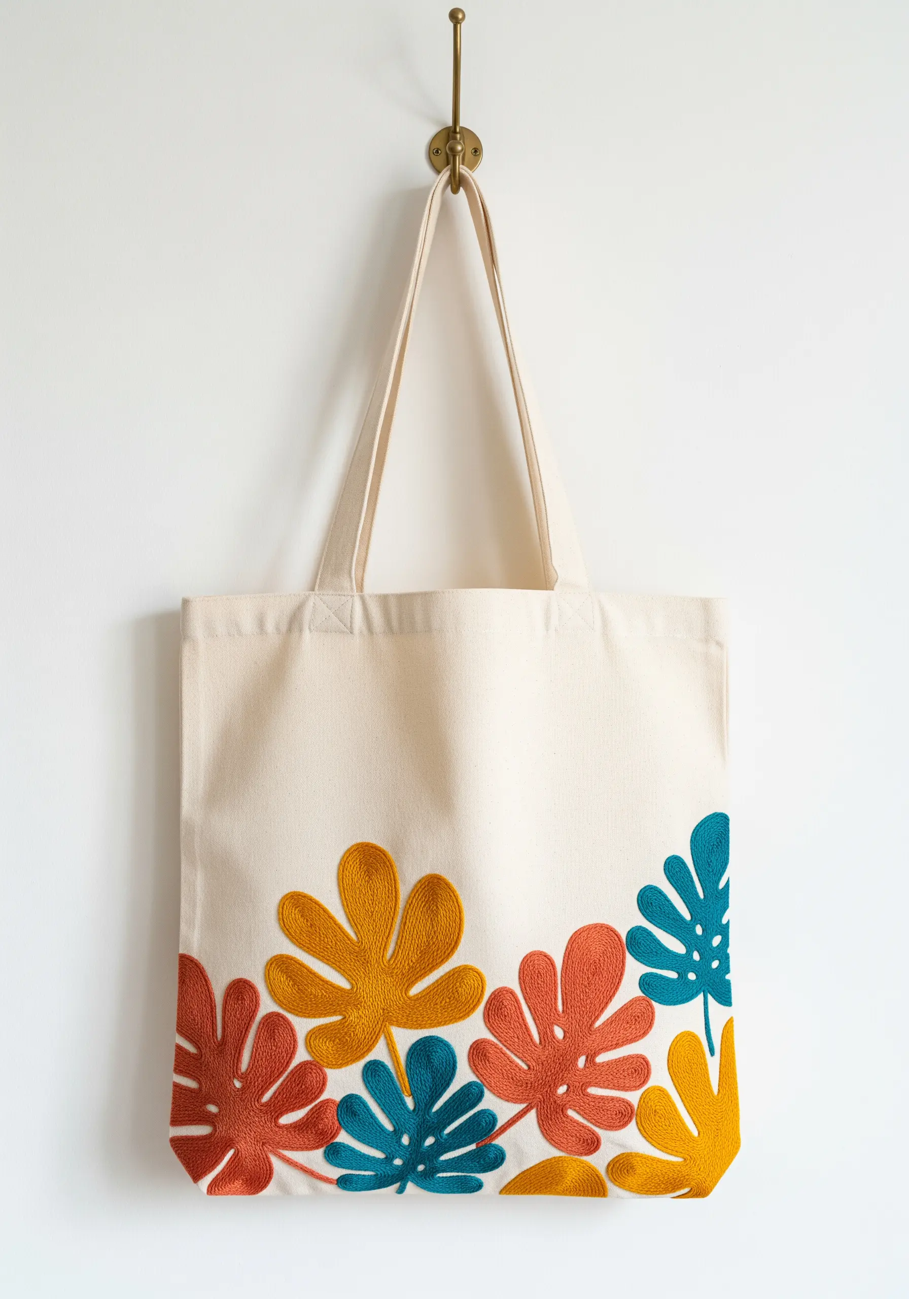 Colorful felt appliqué leaves with embroidered details on a canvas tote bag.