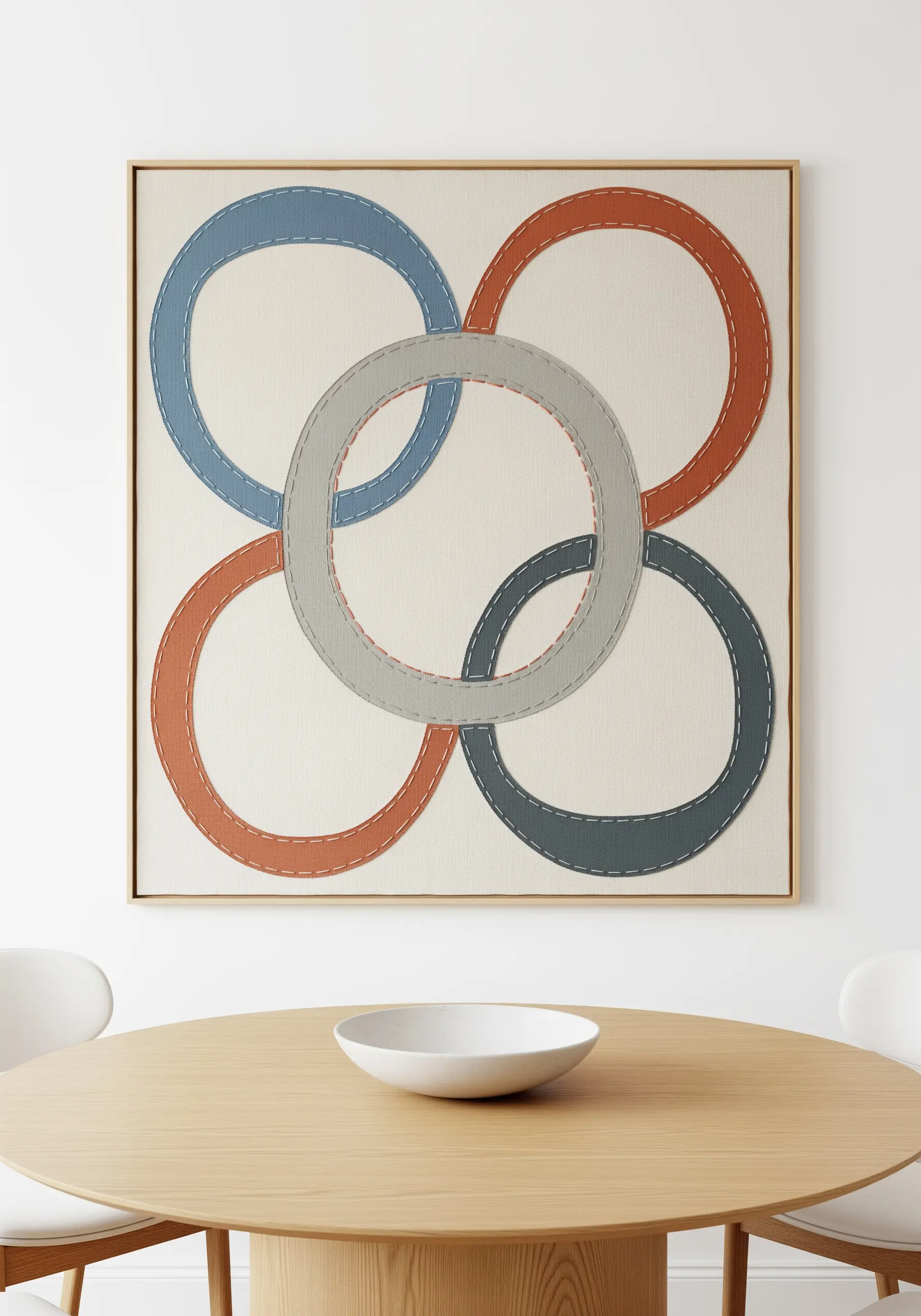 Four interlocking rings in muted colors appliquéd onto canvas with a visible running stitch.