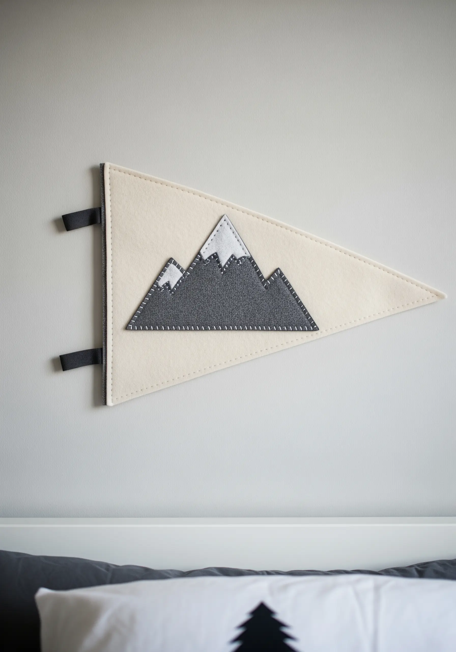 A cream-colored felt pennant decorated with appliqué felt mountains in shades of grey.