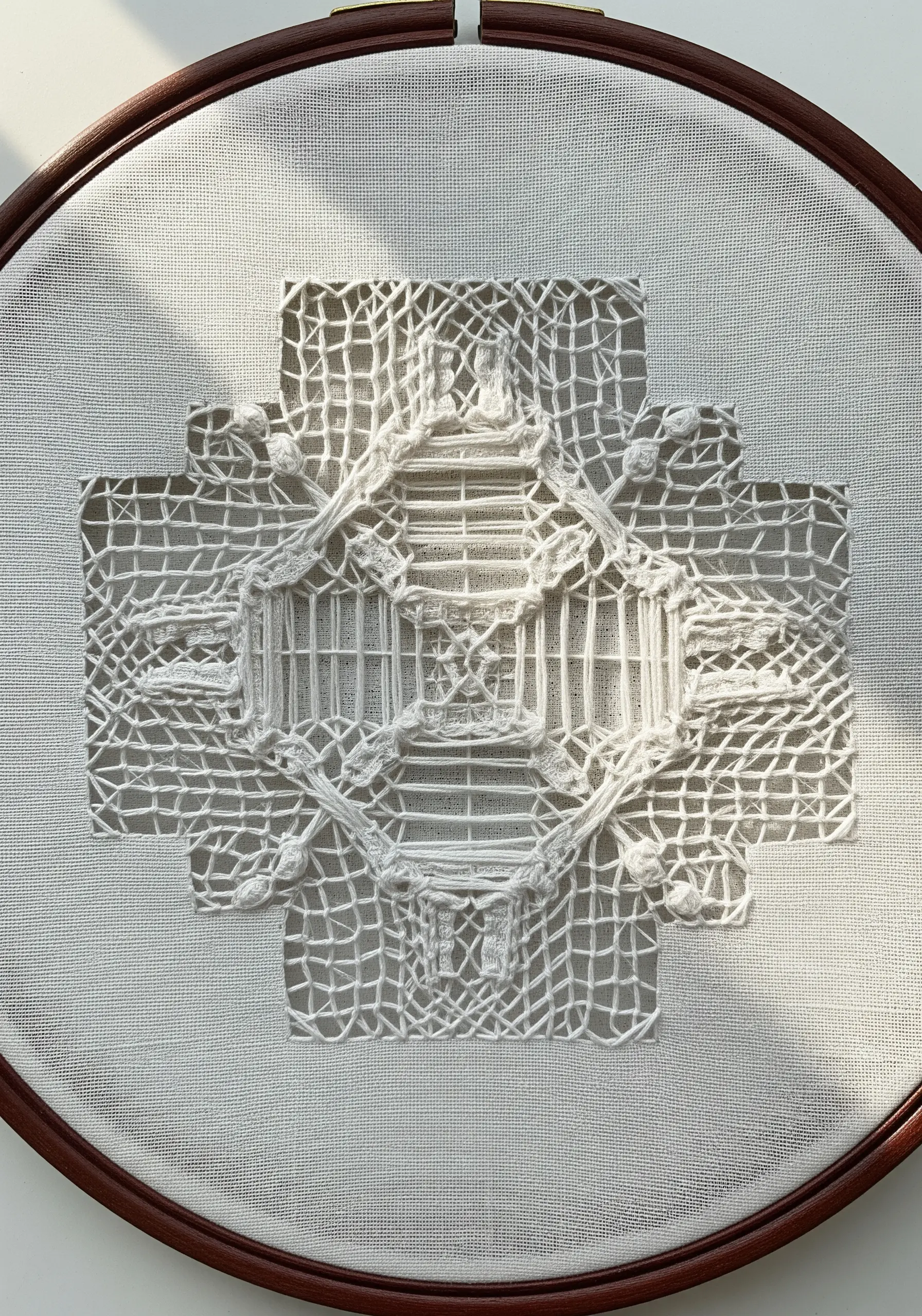 White-on-white cutwork embroidery creating a delicate, architectural lace pattern.