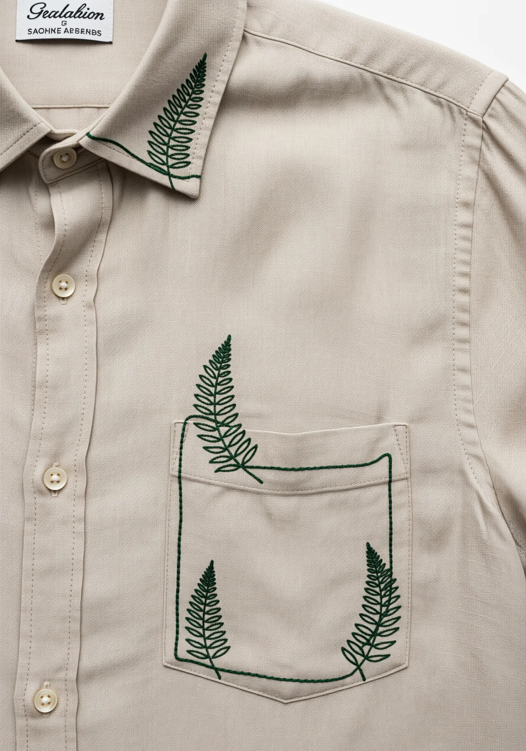 Green fern fronds embroidered to frame the pocket and adorn the collar of a shirt.