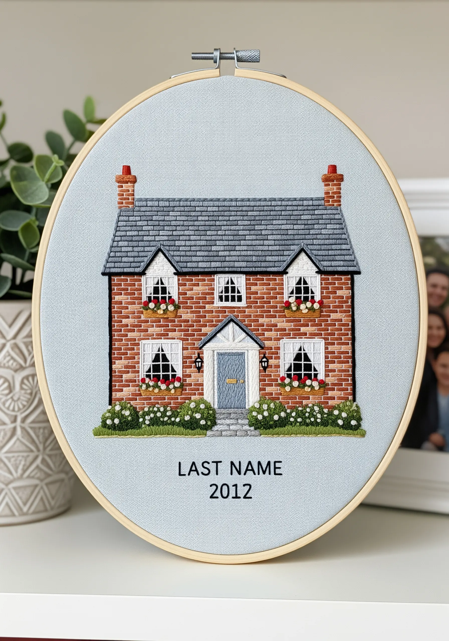 Embroidered portrait of a brick house with personalized last name and year.
