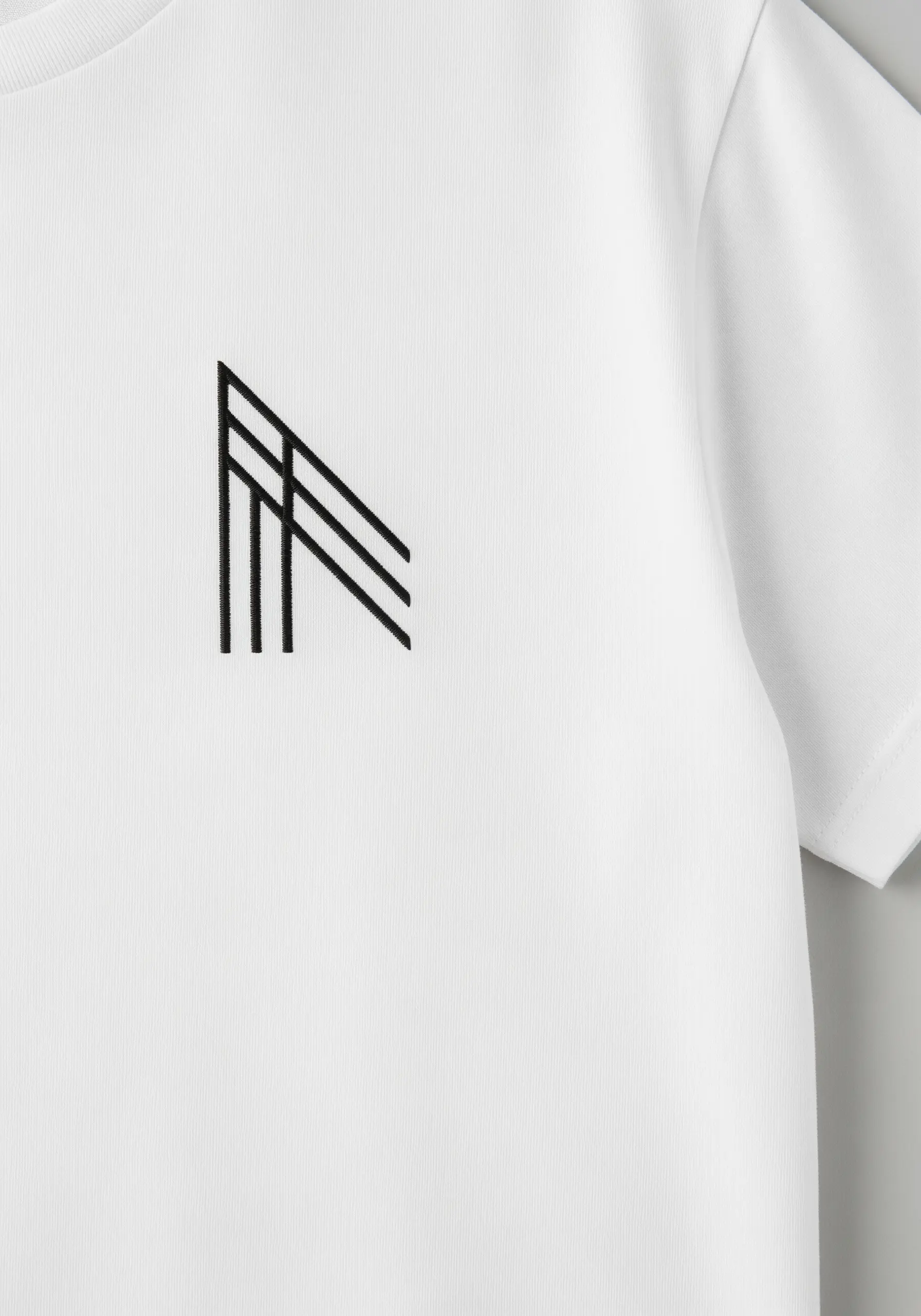 Minimalist geometric line motif embroidered in black on a white t-shirt.