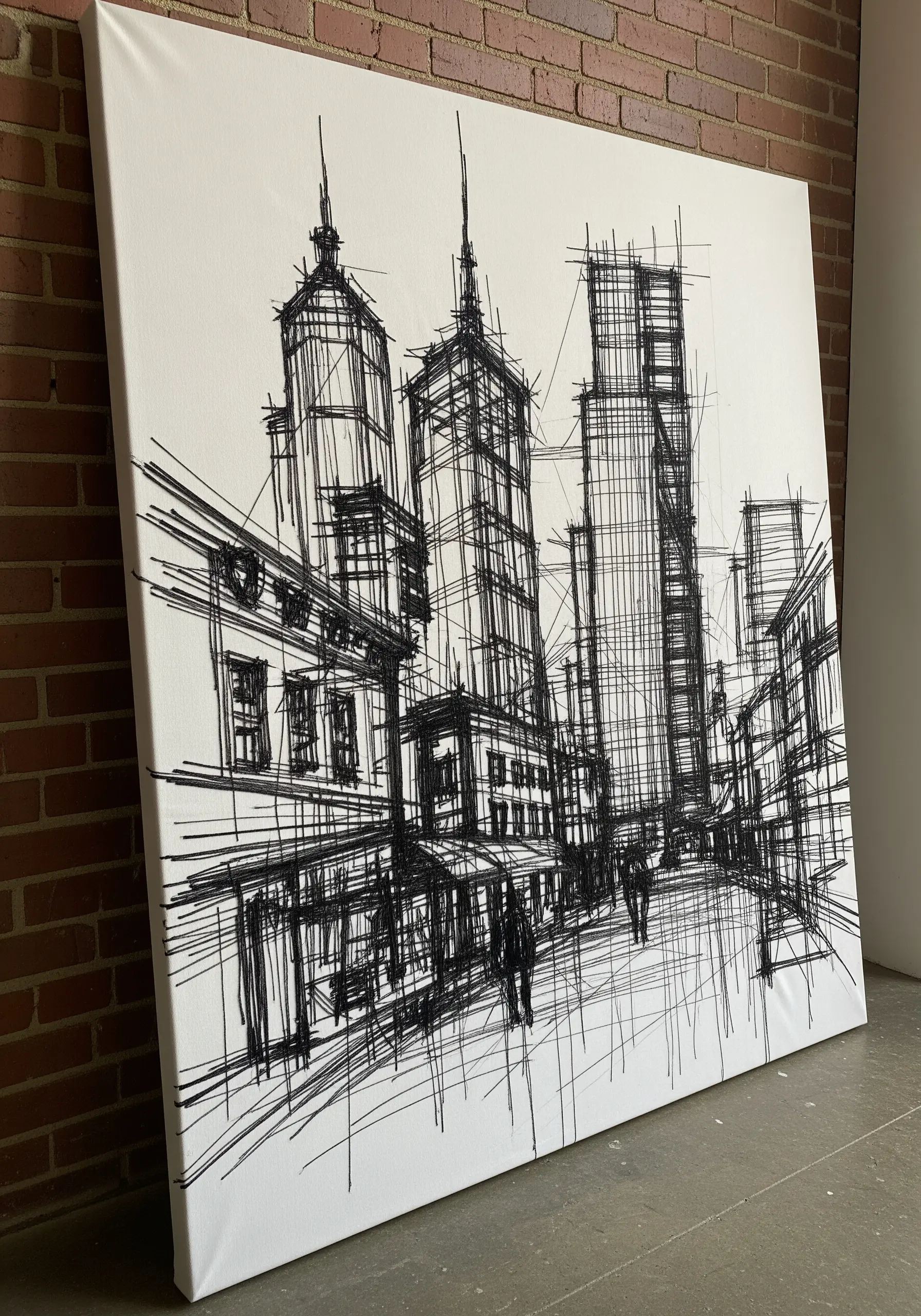 Black thread embroidery on white canvas depicting a sketch-style cityscape