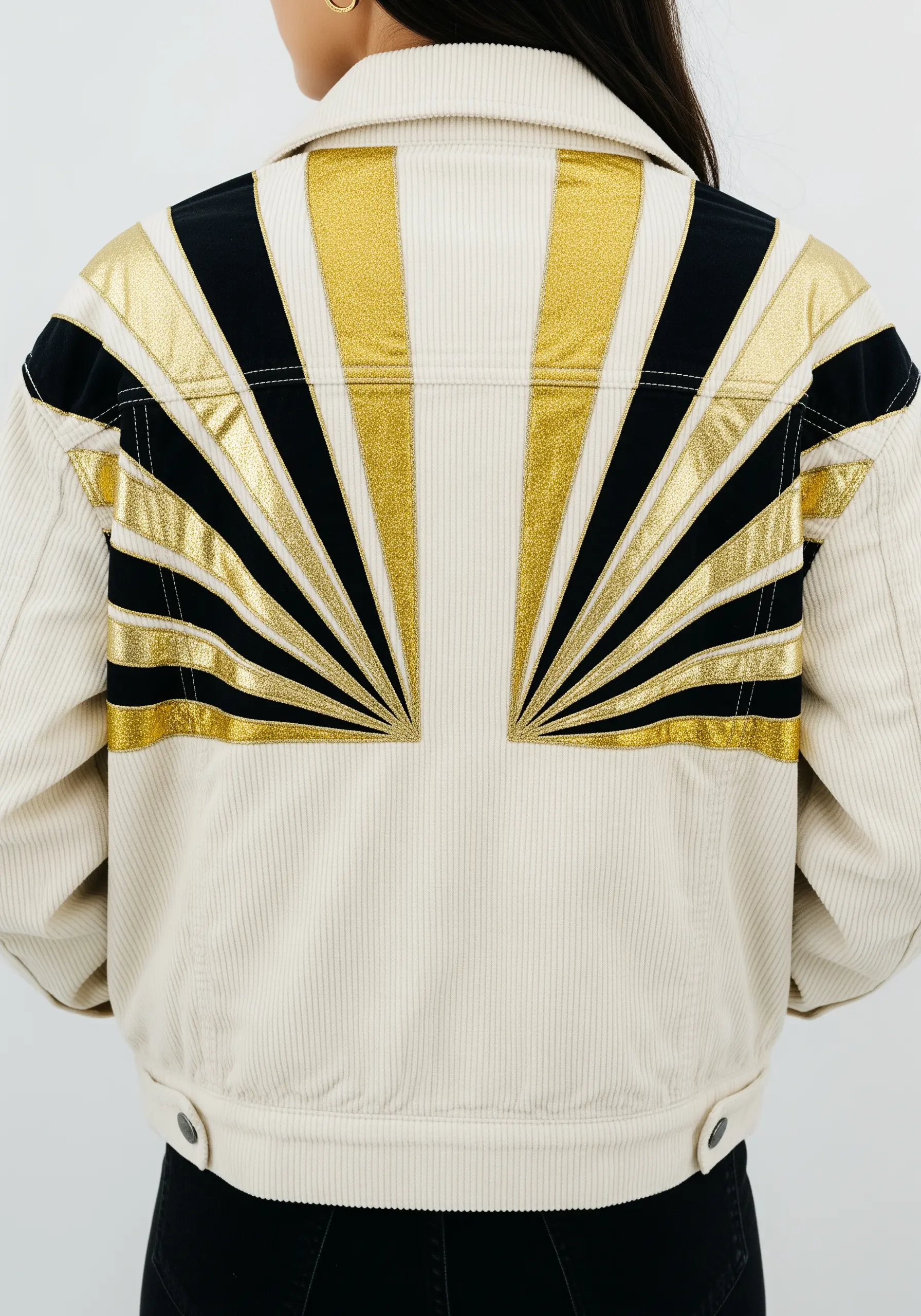 Gold and black Art Deco sunburst design on the back of a white corduroy jacket.