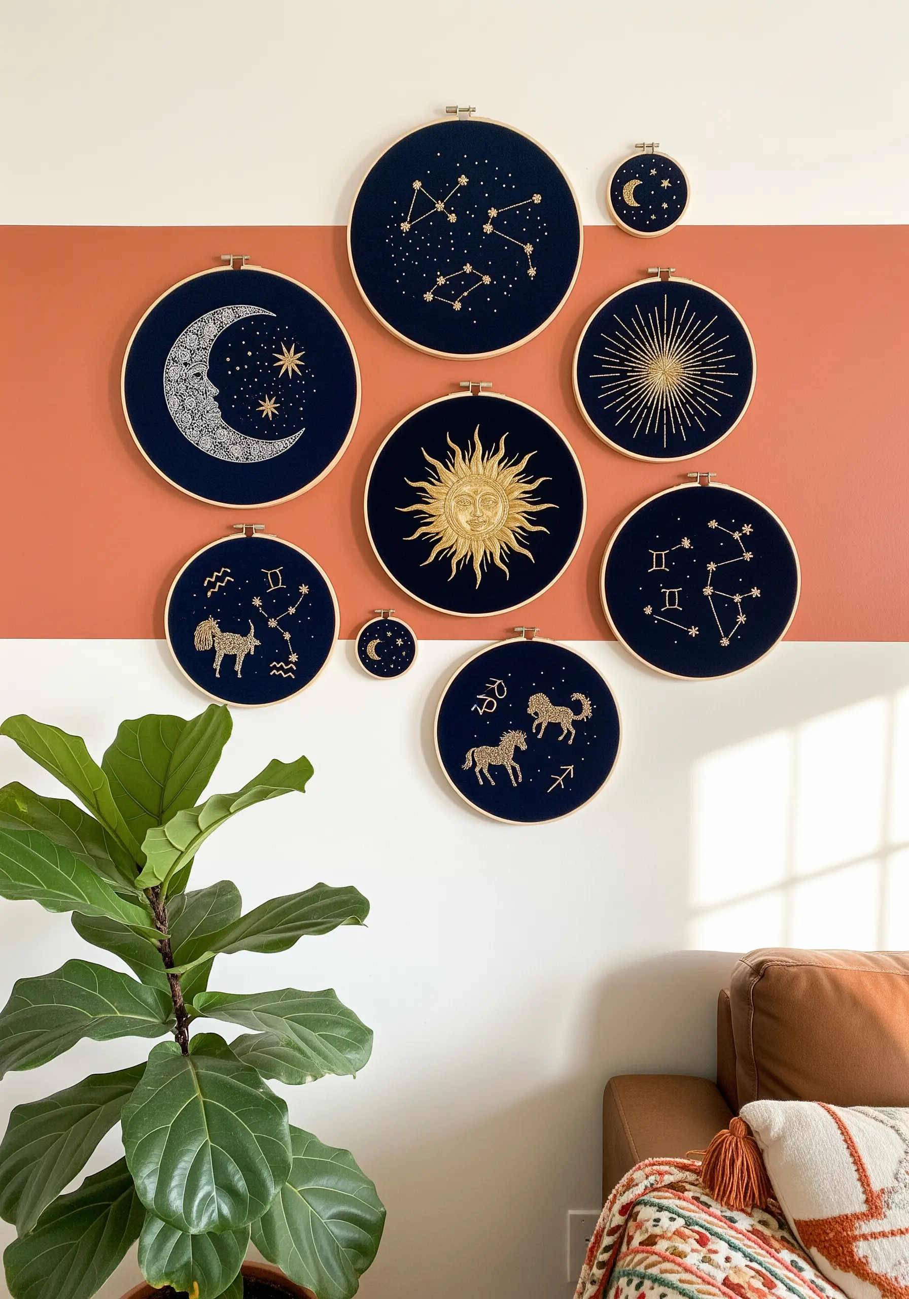 A gallery wall of nine embroidery hoops featuring gold celestial and zodiac designs on black fabric.