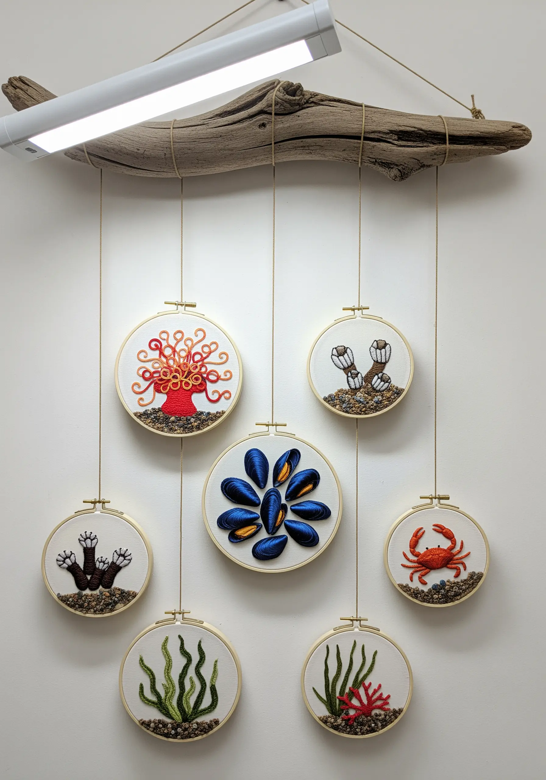 A mobile made of a driftwood branch and small embroidery hoops of sea creatures.