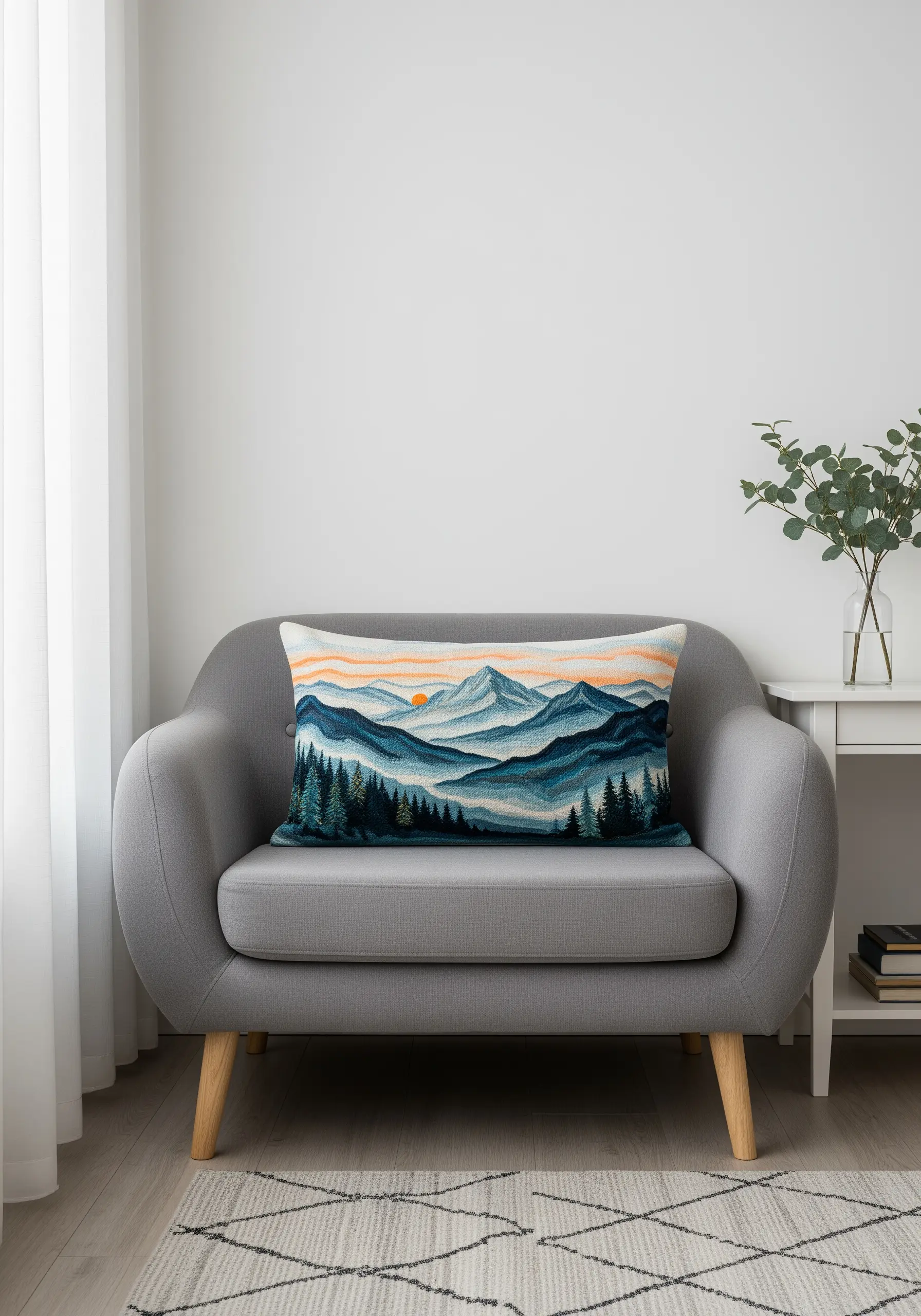 An embroidered lumbar pillow depicting layers of mountains in shades of blue and green.