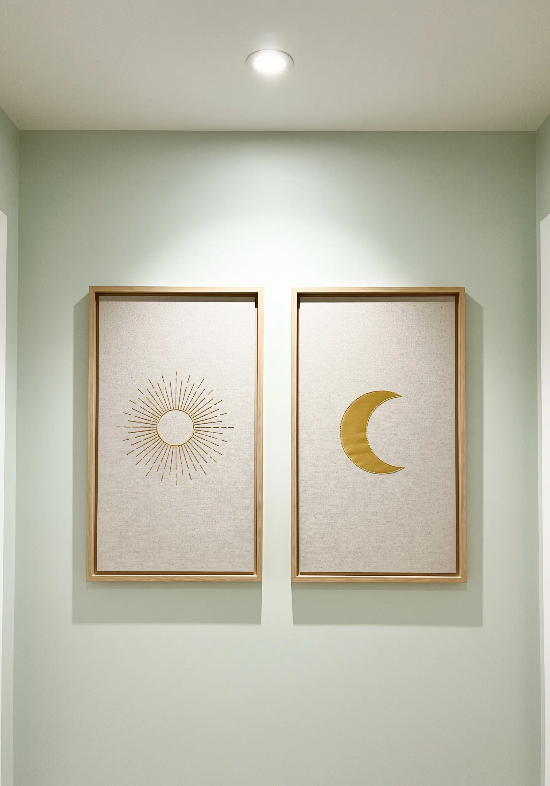 A diptych of framed embroideries: one of a sun with gold rays, the other a gold satin-stitched moon.