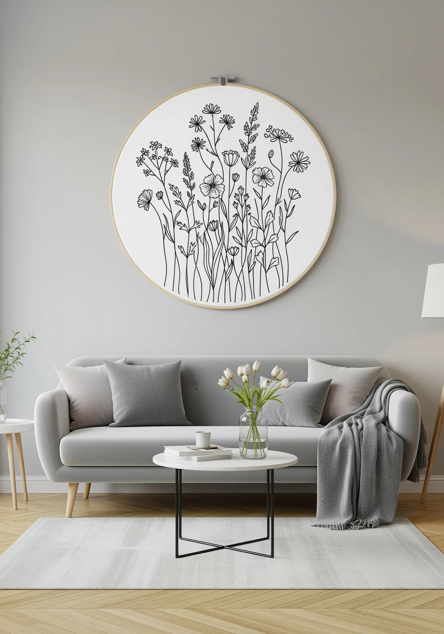 A large embroidery hoop filled with a detailed line-art drawing of a wildflower meadow.