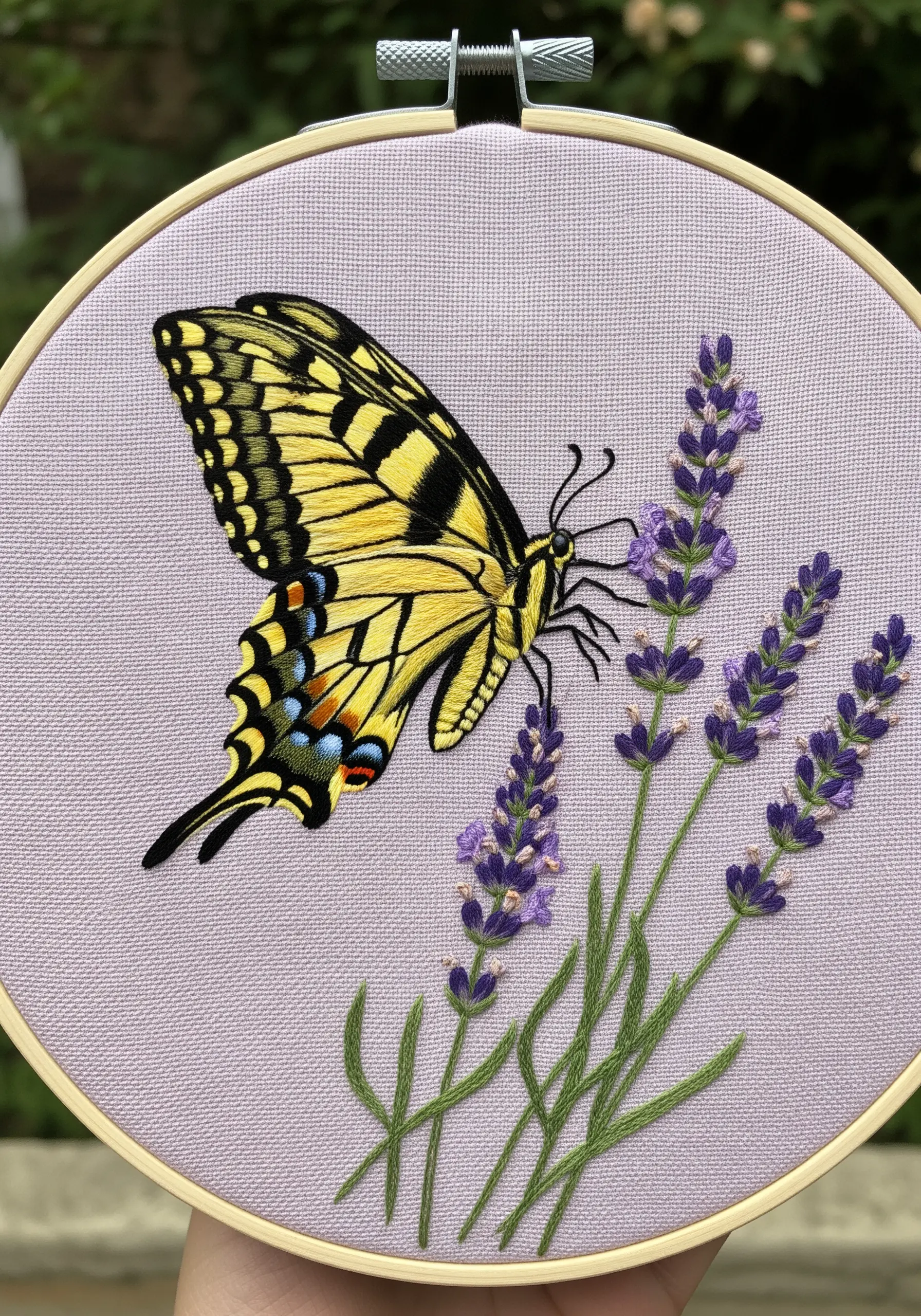 A yellow swallowtail butterfly embroidered on lavender-colored fabric with purple lavender sprigs.