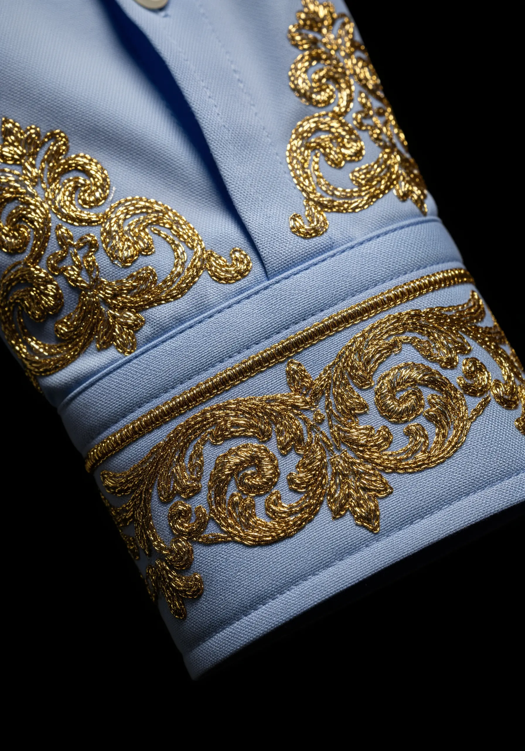 Light blue shirt cuff embellished with heavy, ornate gold baroque embroidery