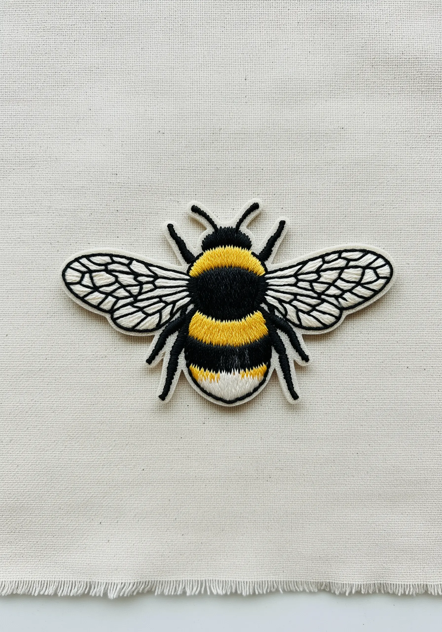 A realistic bumblebee patch showing thread-painted texture on the body and delicate wing details.