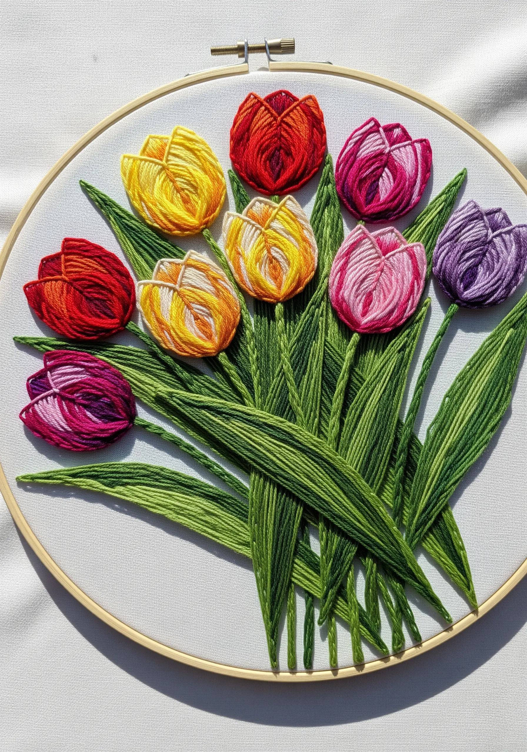 A vibrant bouquet of embroidered tulips in yellow, red, pink, and purple on white fabric.