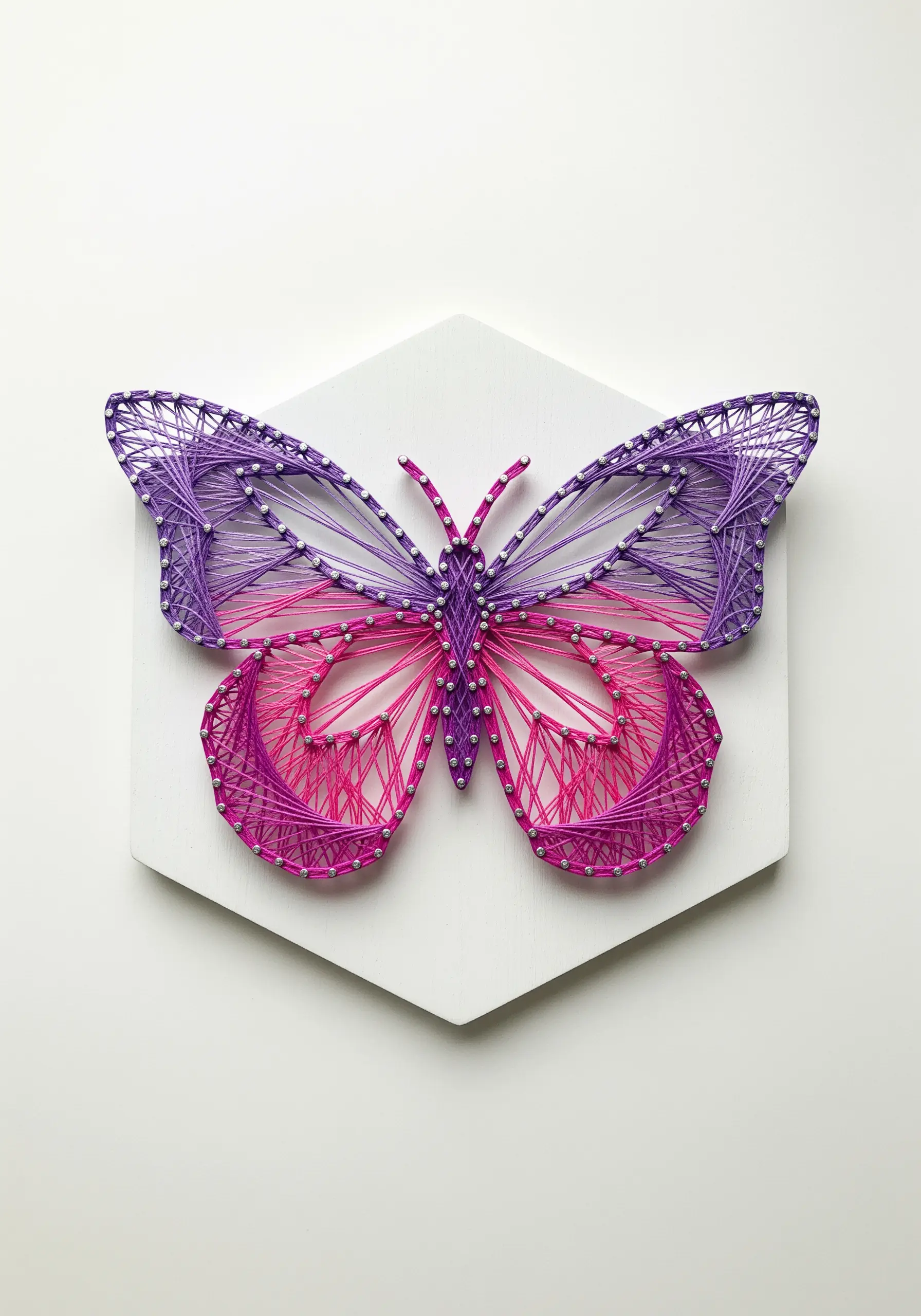 A butterfly with wings that blend seamlessly from purple to pink using a long-and-short stitch.