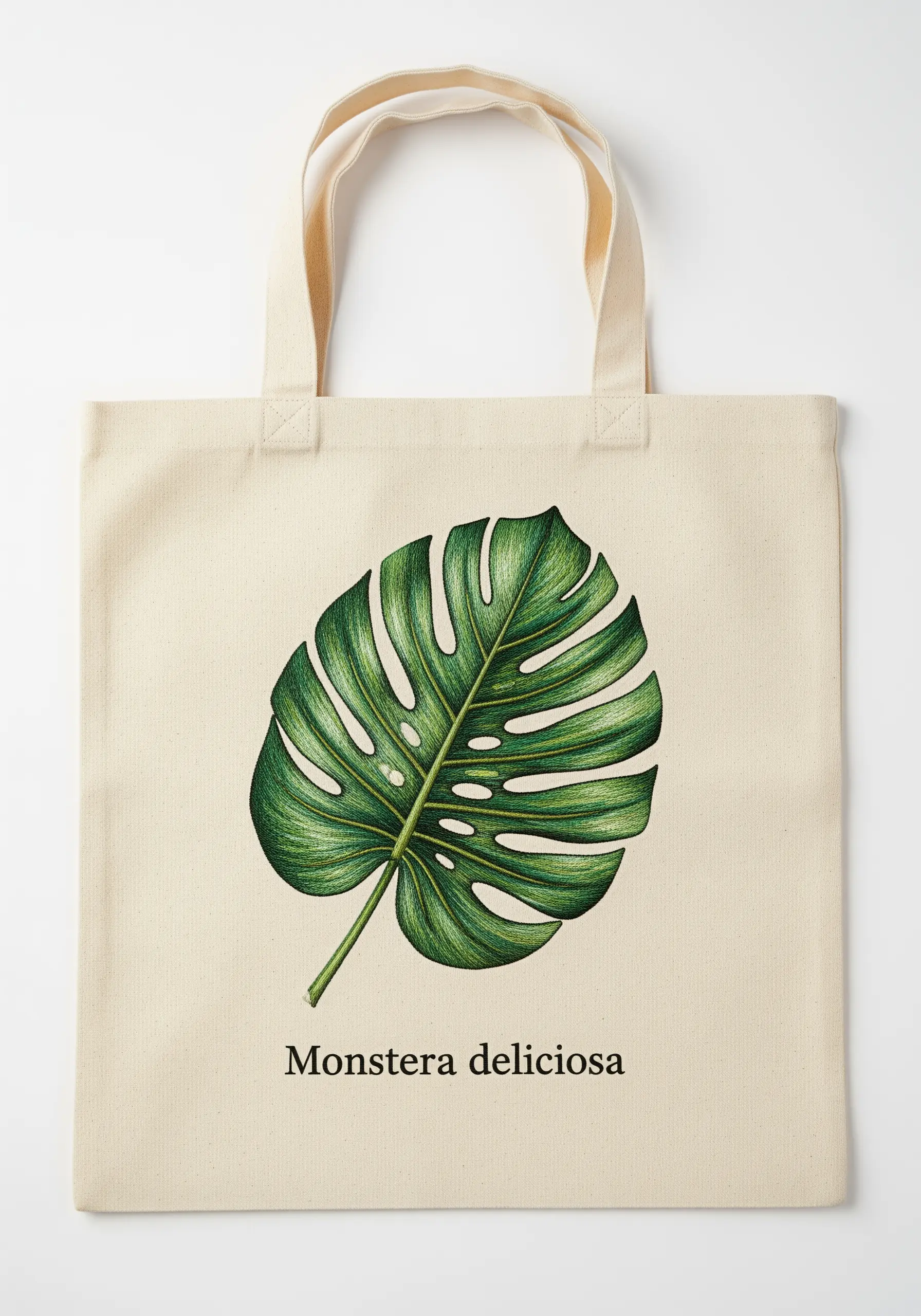 A realistic Monstera leaf embroidered on a canvas tote using thread painting for color gradients.