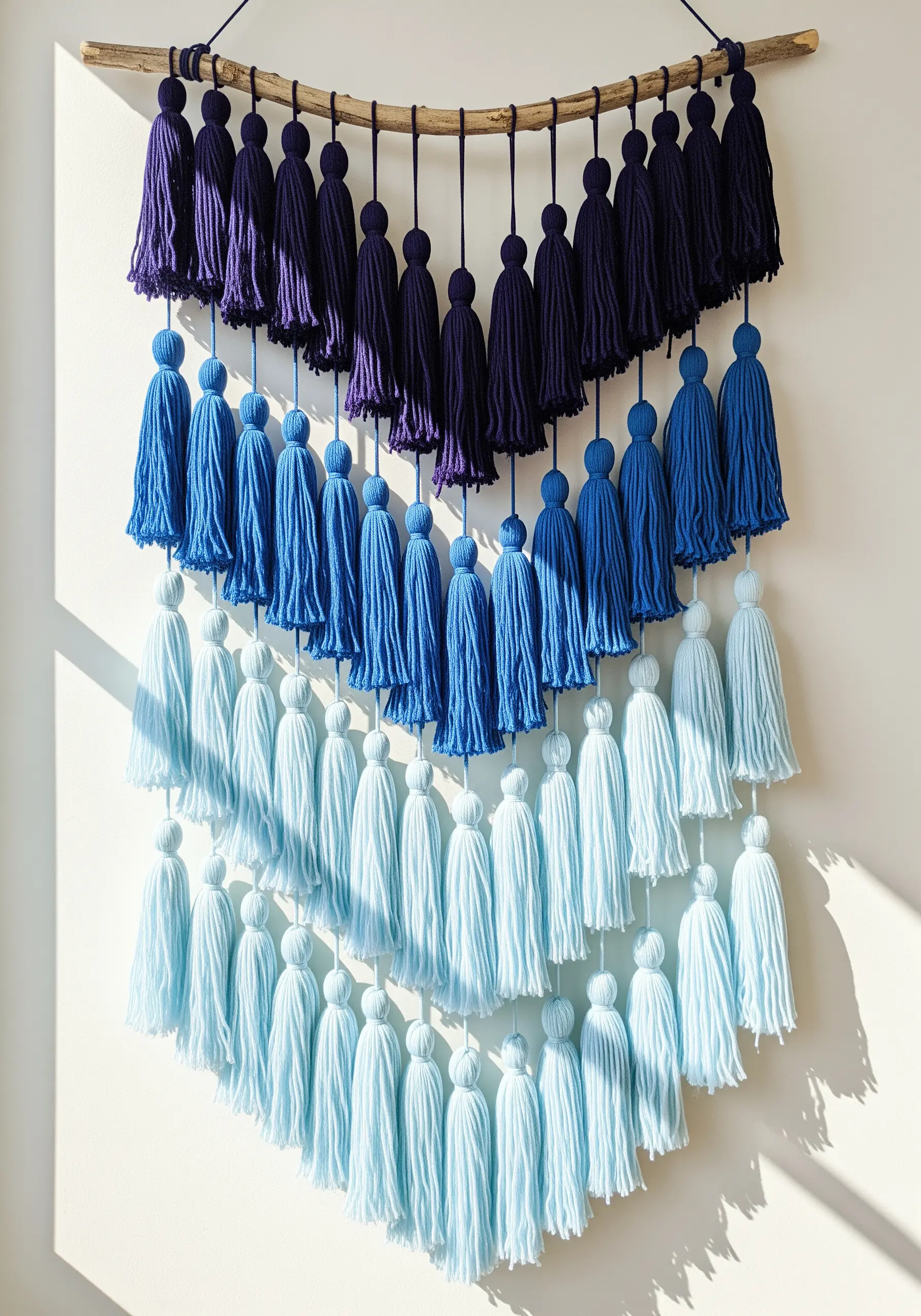 A V-shaped wall hanging made of yarn tassels arranged in a blue gradient.