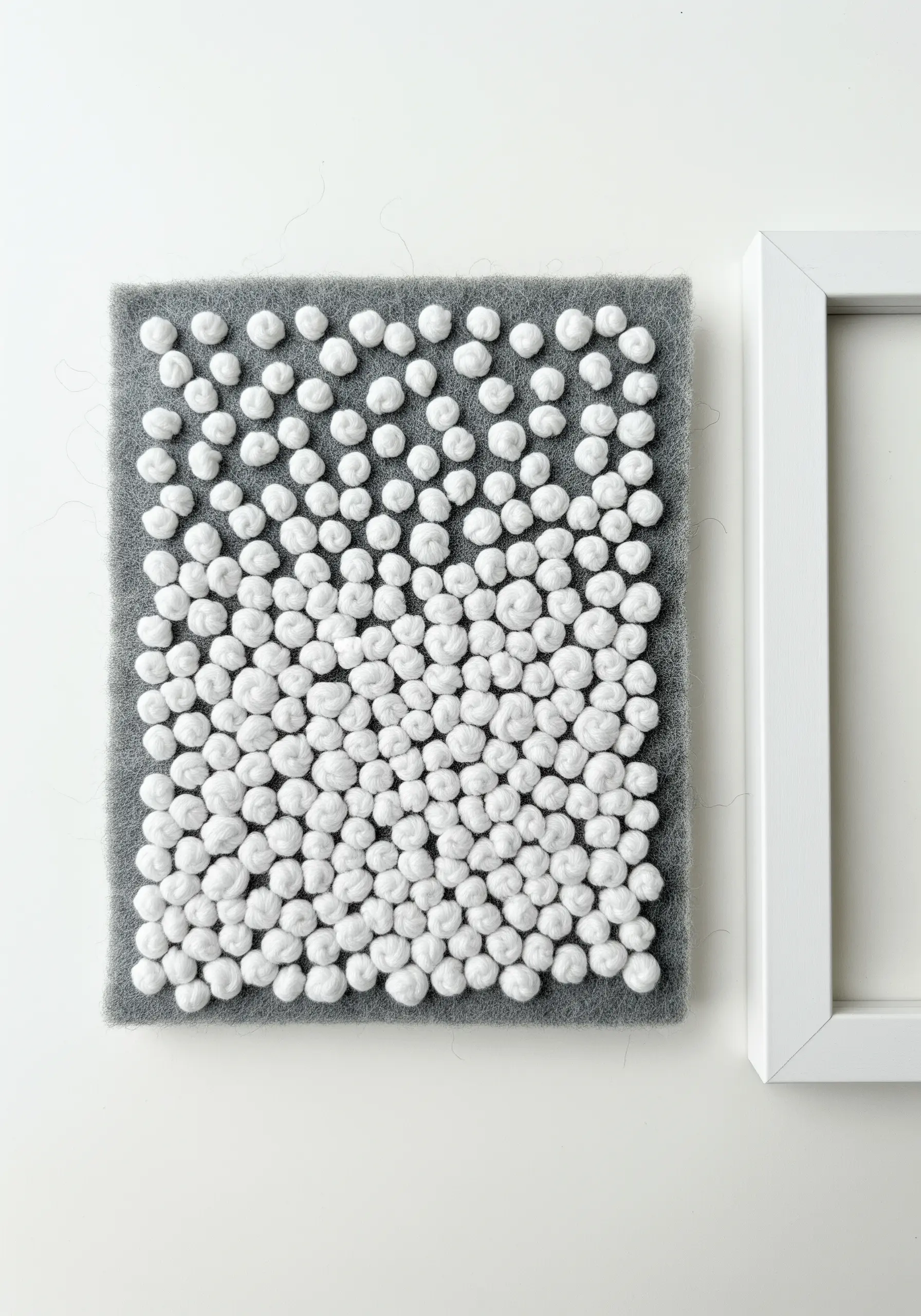 A dense, textural gradient of white and gray knots on a felt background.