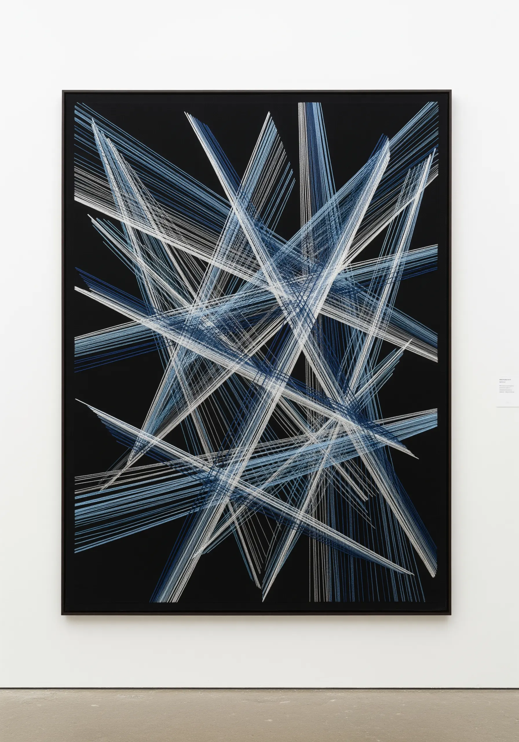 Geometric abstract art made with layered straight stitches in shades of blue and white on black fabric.