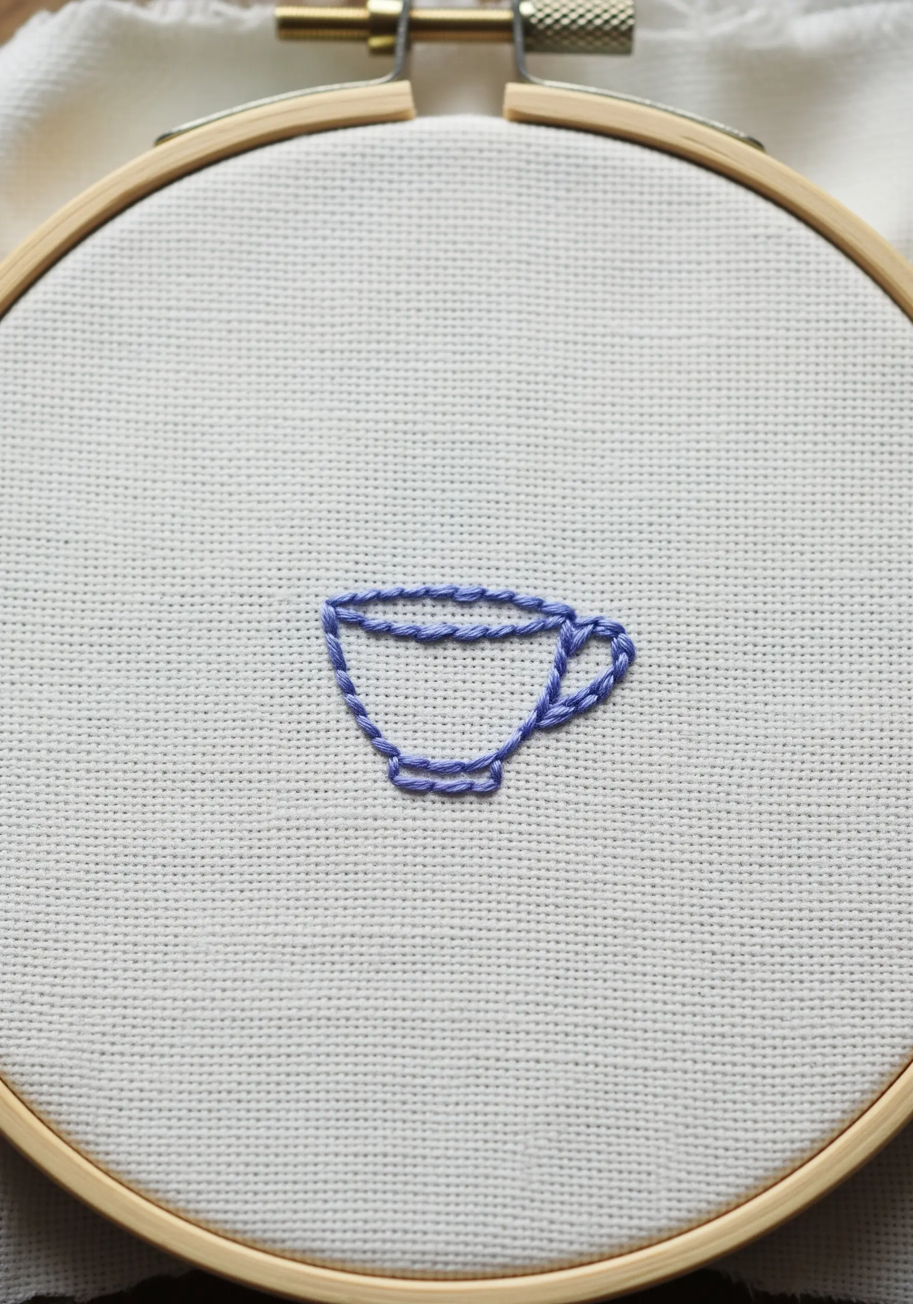 Outline of a teacup created with linked detached chain stitches.
