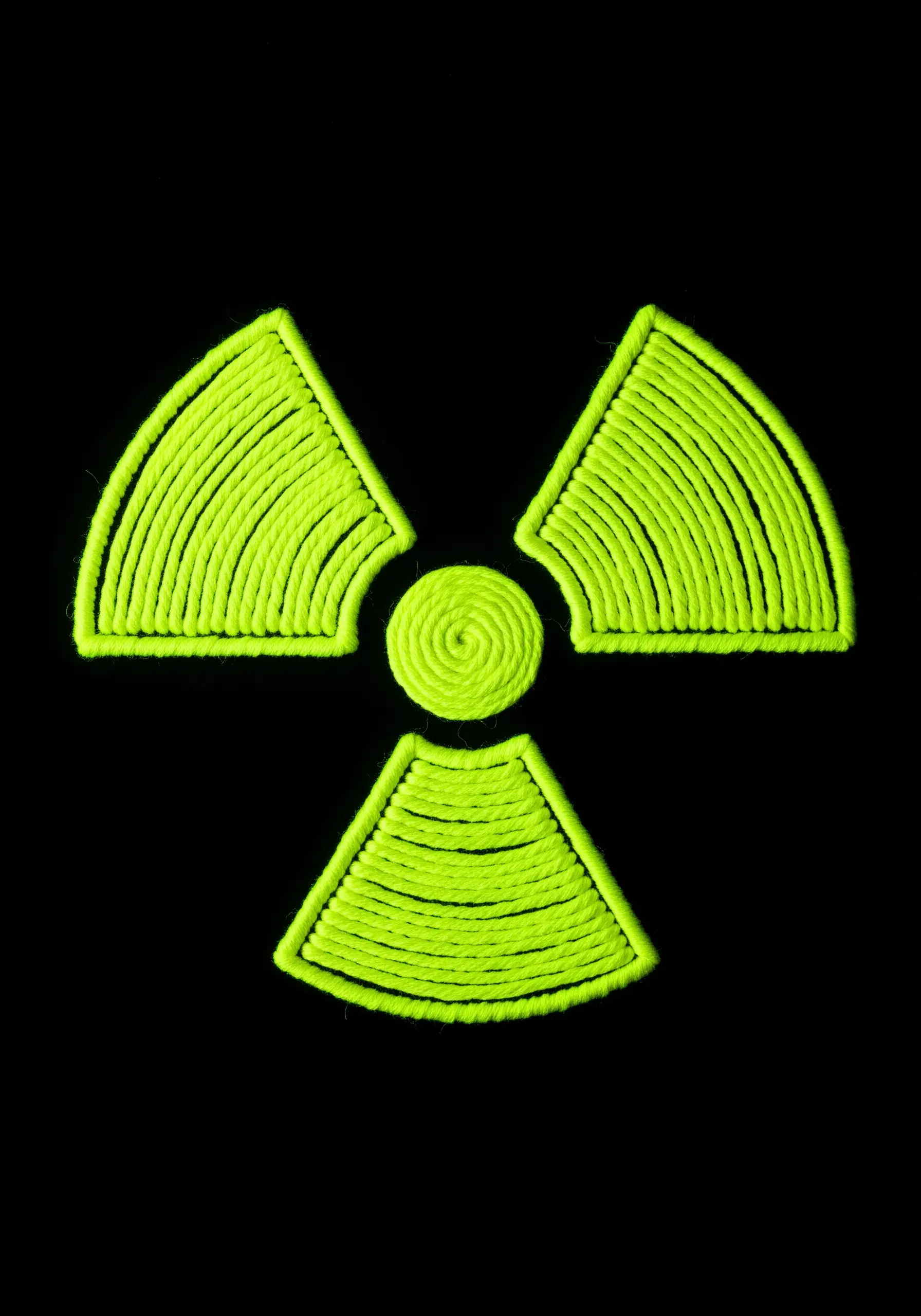 A radioactive symbol filled in with dense, textured neon yellow-green thread.