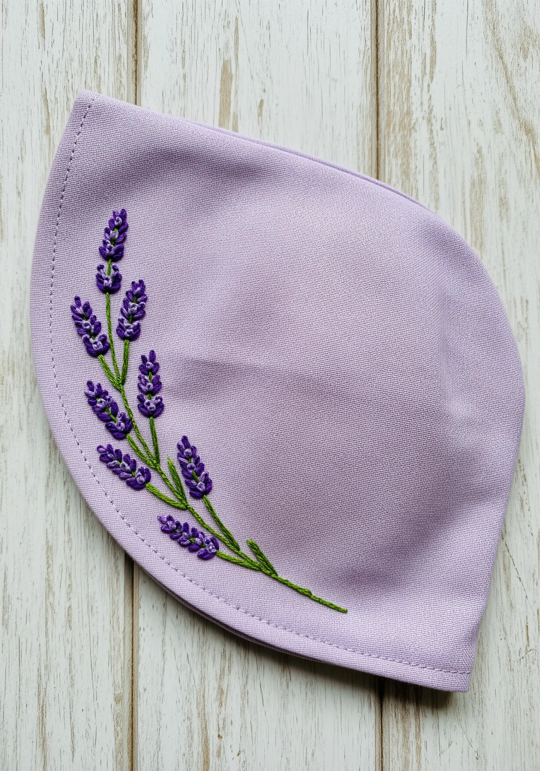 A sprig of lavender embroidered on a bonnet with textured French knots for blossoms.