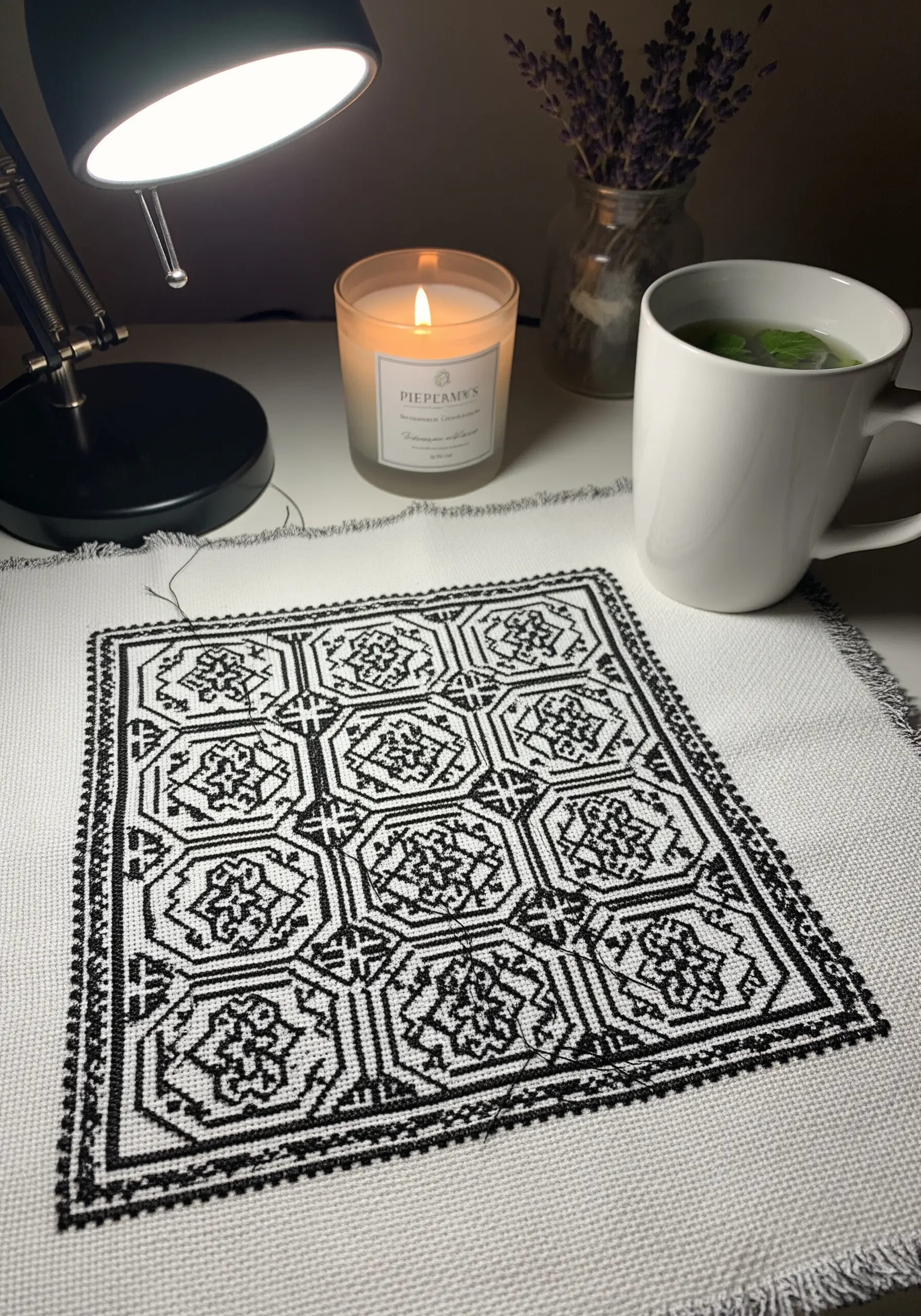 A blackwork embroidery project with a complex geometric tile pattern on white fabric.