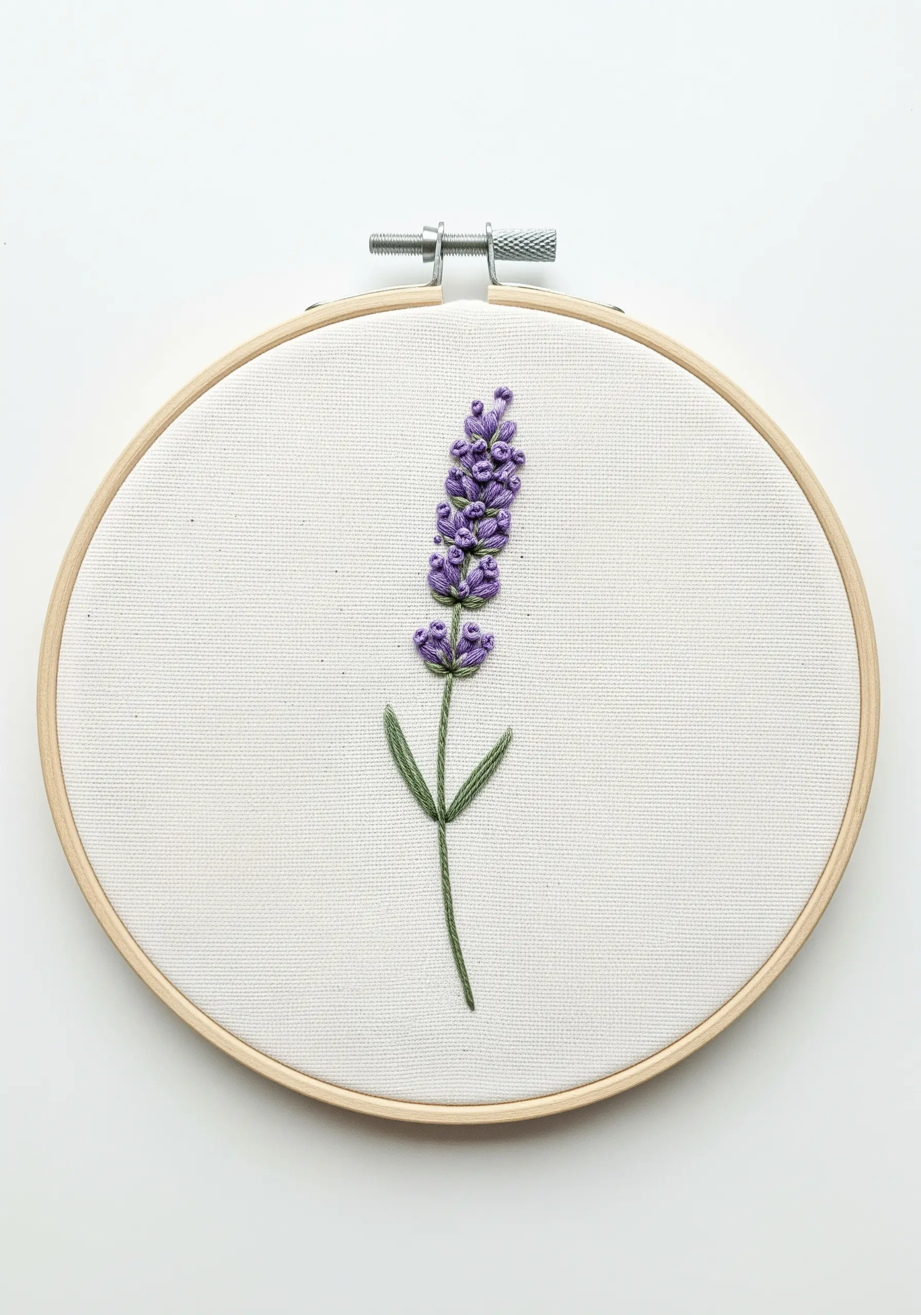 A stalk of lavender embroidered with purple bullion knots and a green stem on white fabric.