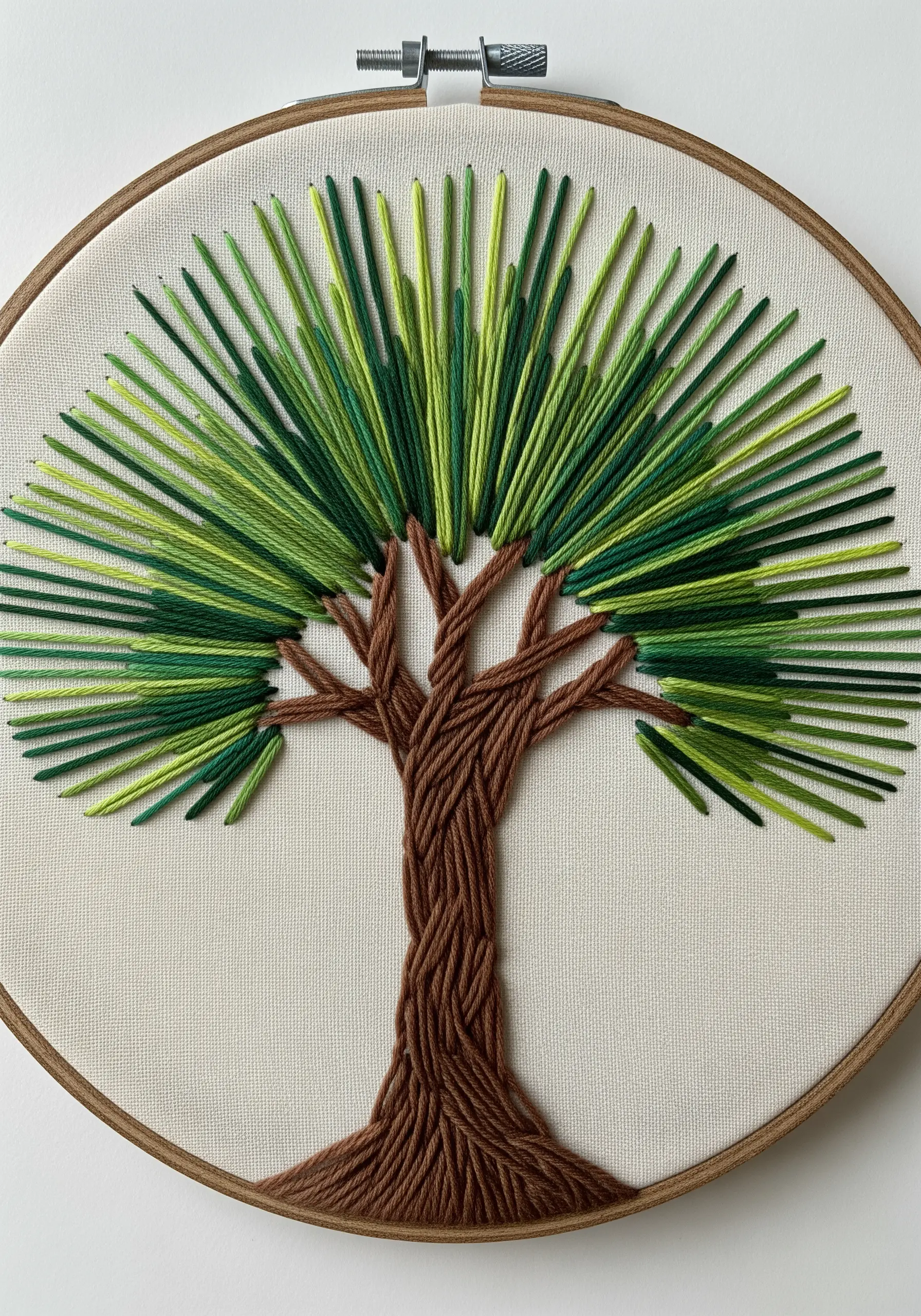 An embroidered tree with a full canopy made from radiating straight stitches in shades of green.