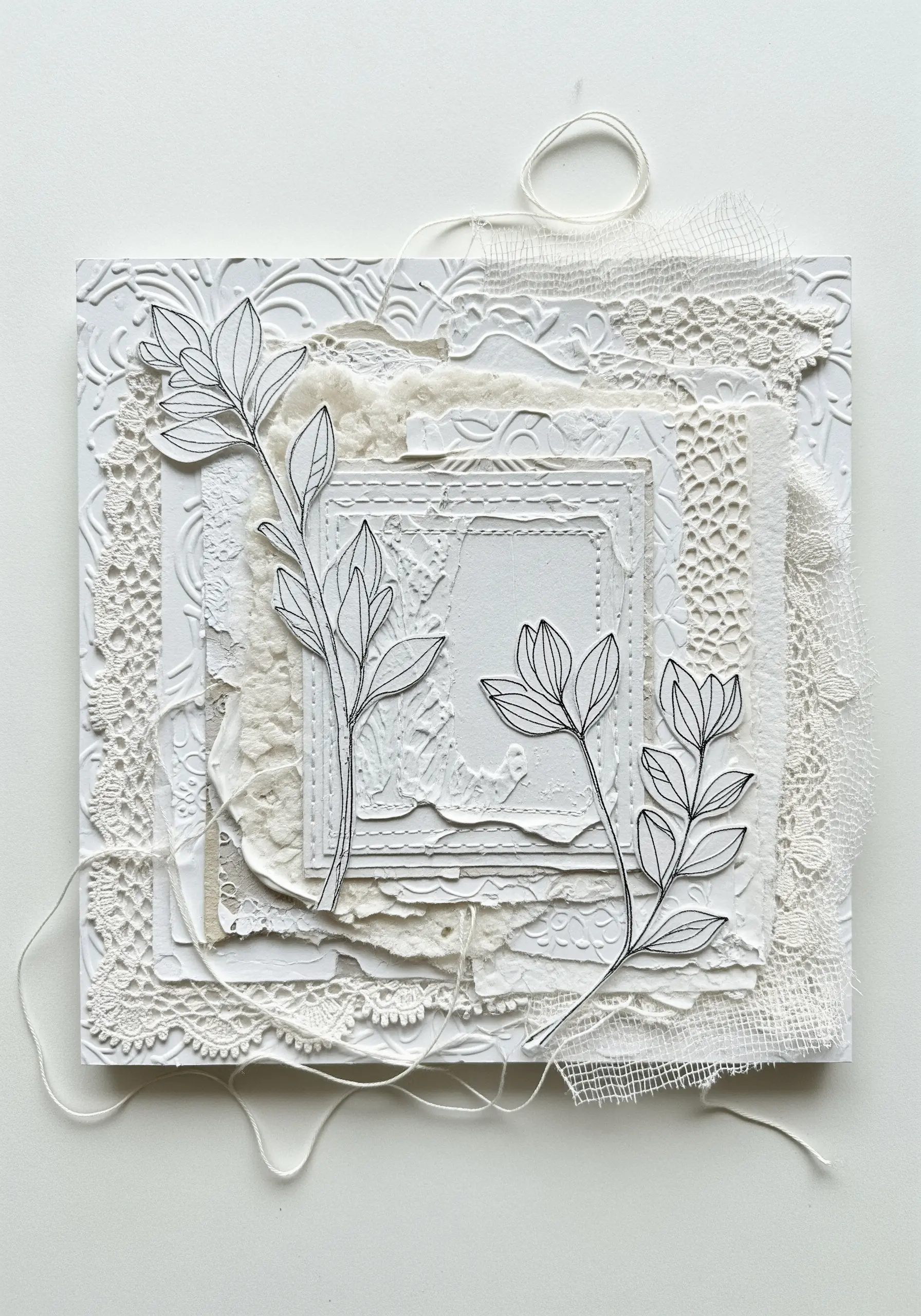 A white-on-white collage of lace, embossed paper, and gauze with stitched line drawings.