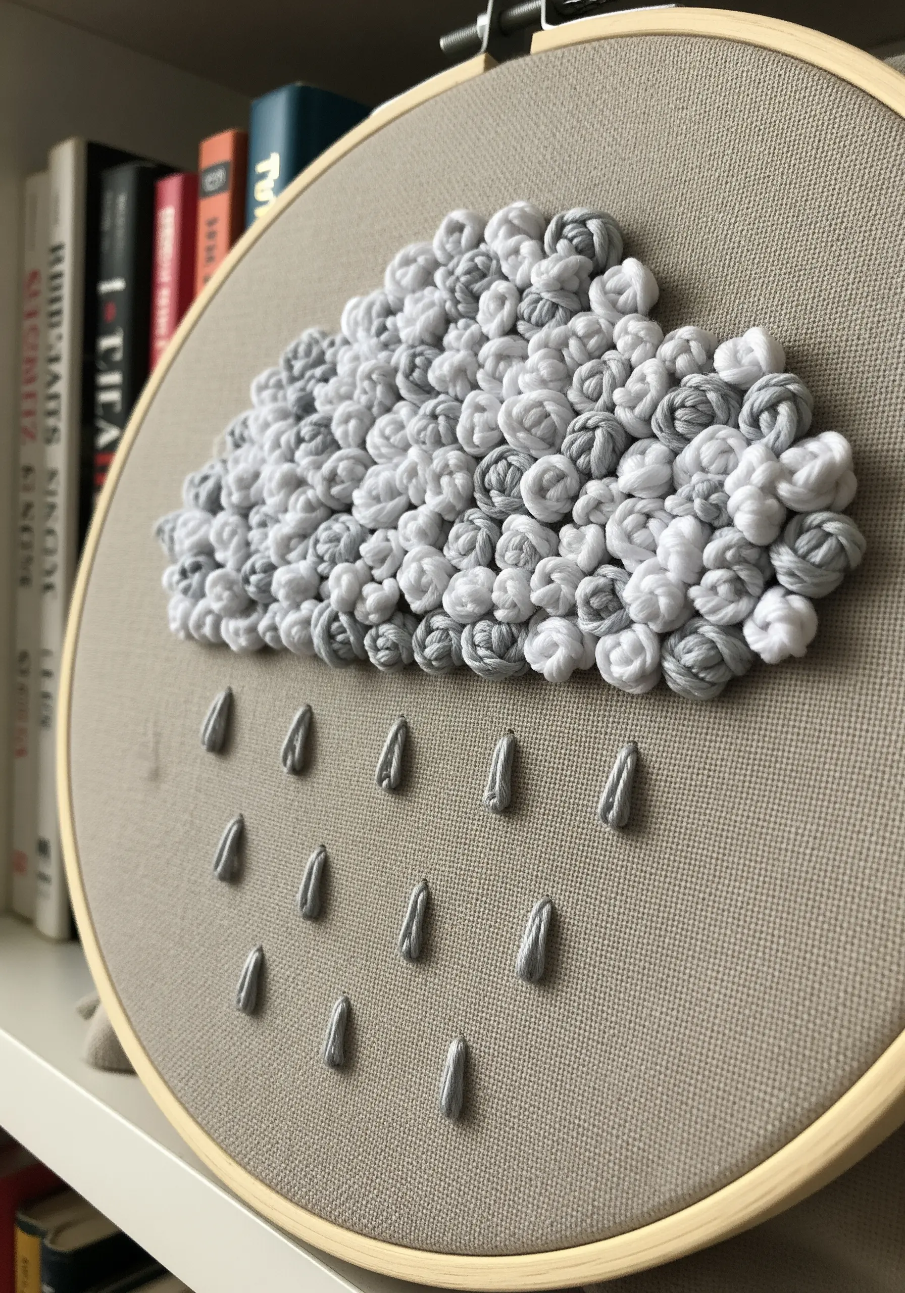 Gray and white woven wheel stitches forming a cloud with silver raindrops.