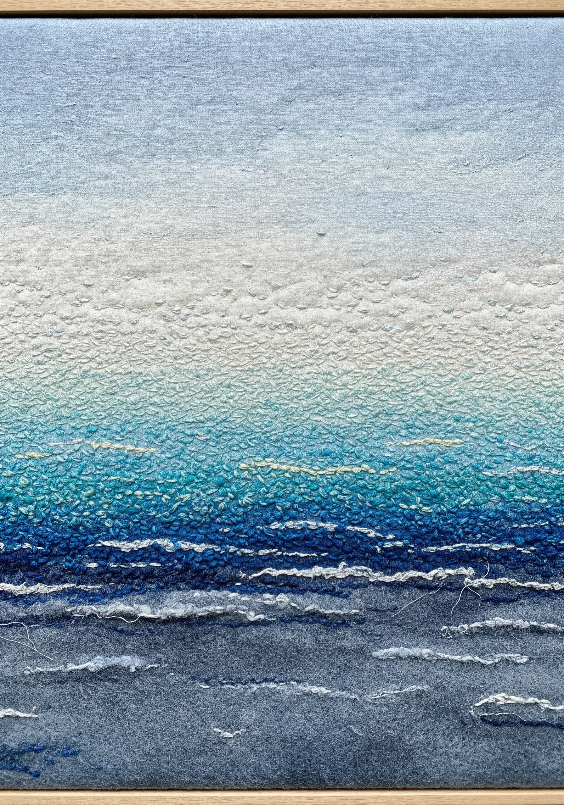 An abstract ocean scene with a painted gradient base and dense textural stitching.