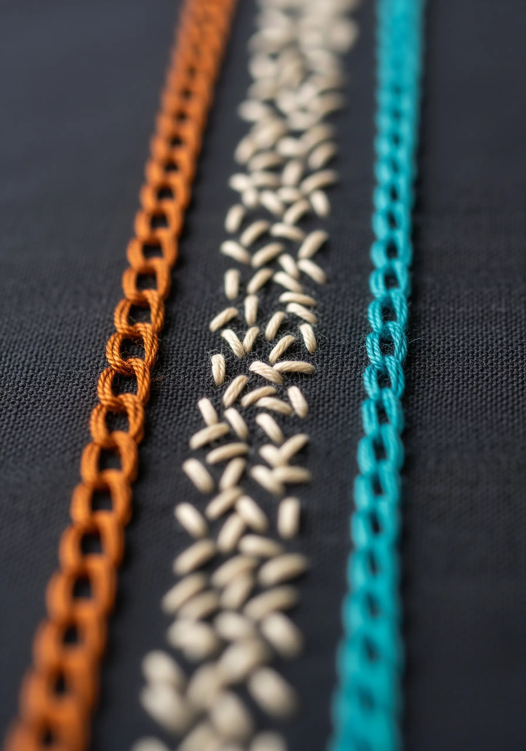 A stitch sampler showing three different decorative line stitches in orange, cream, and teal.
