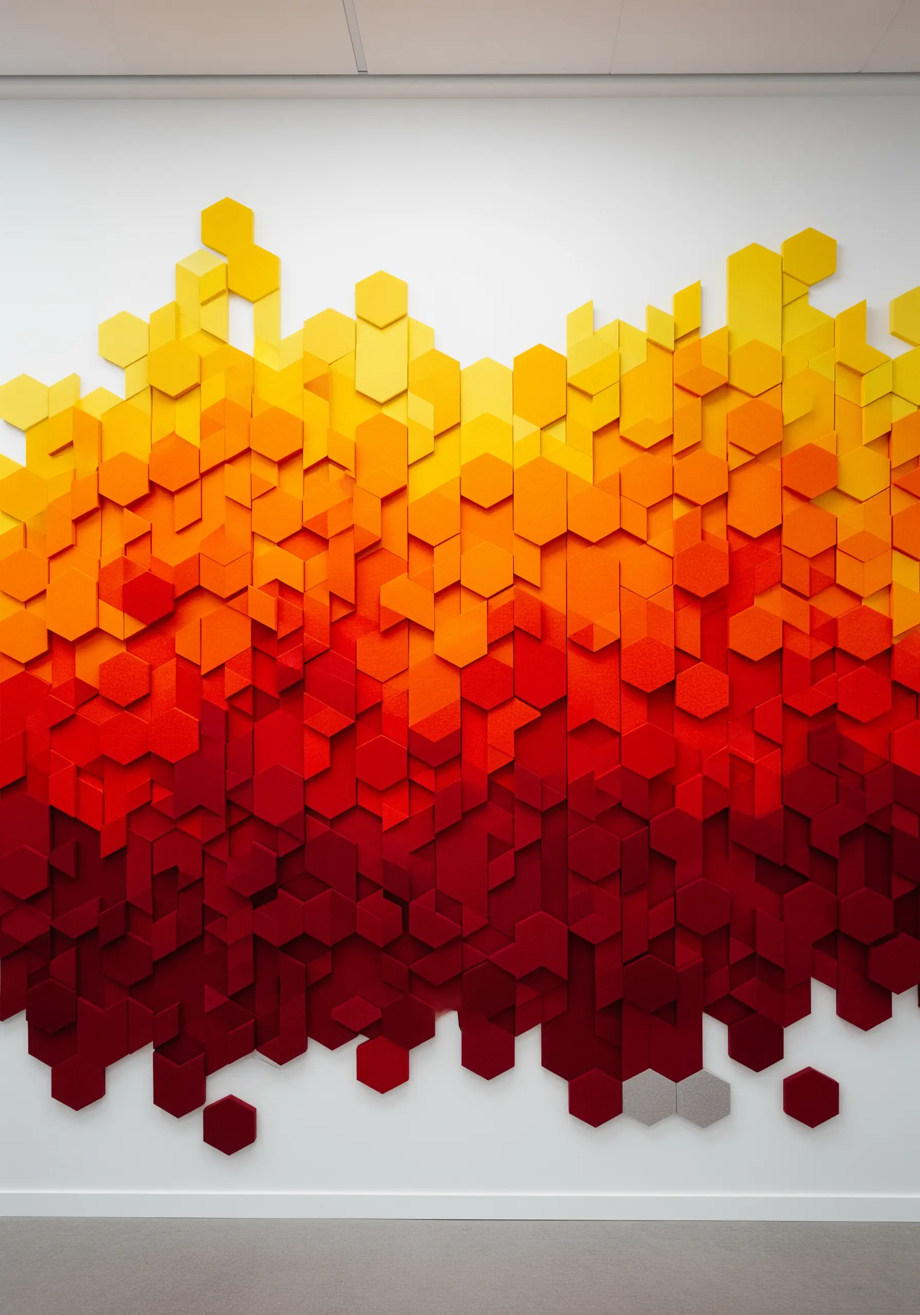 A wall covered in hexagonal felt tiles arranged in a fiery yellow, orange, and red gradient.