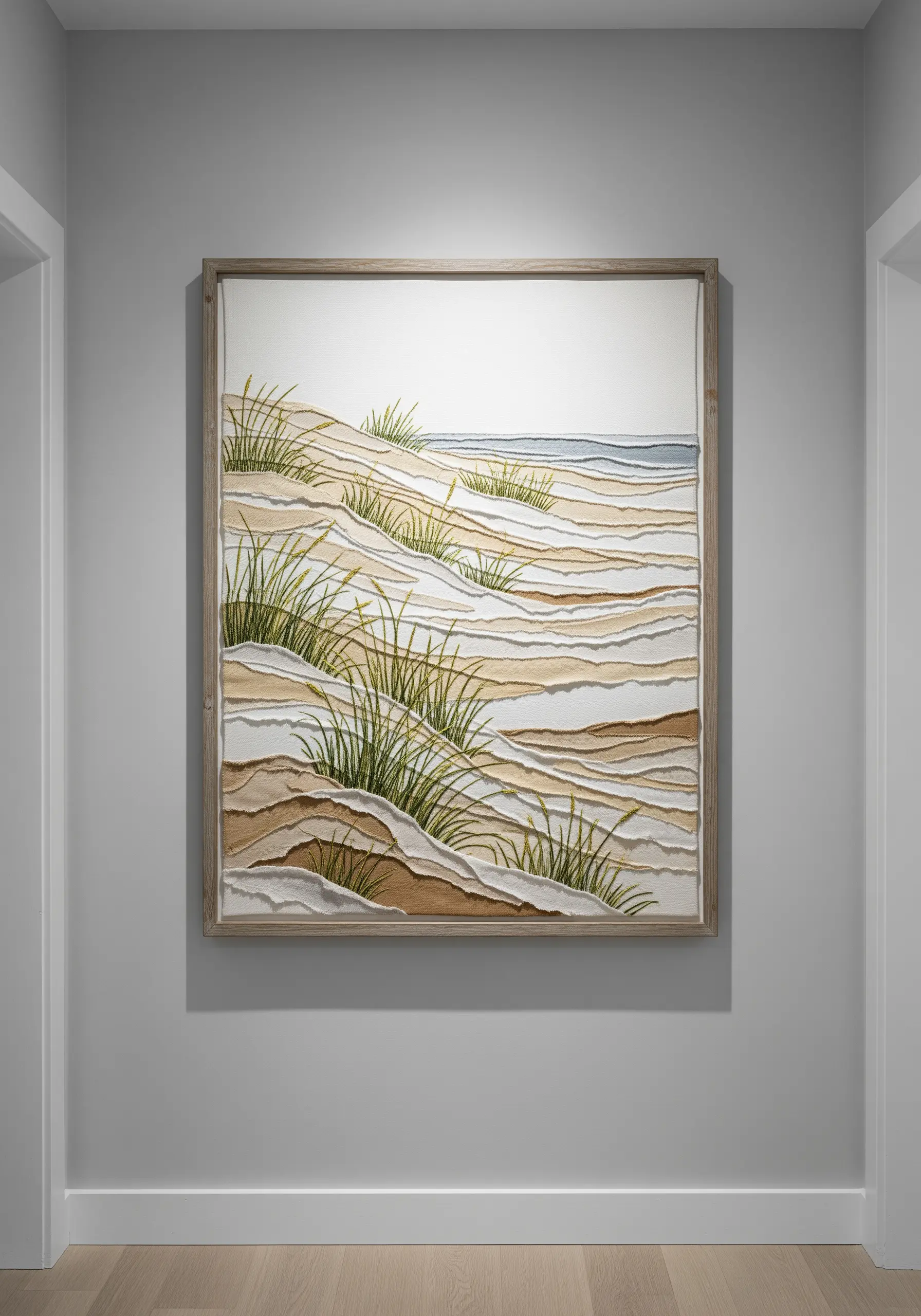 Framed embroidery of sand dunes created with layered, raw-edge fabric appliqué and stitched grass.