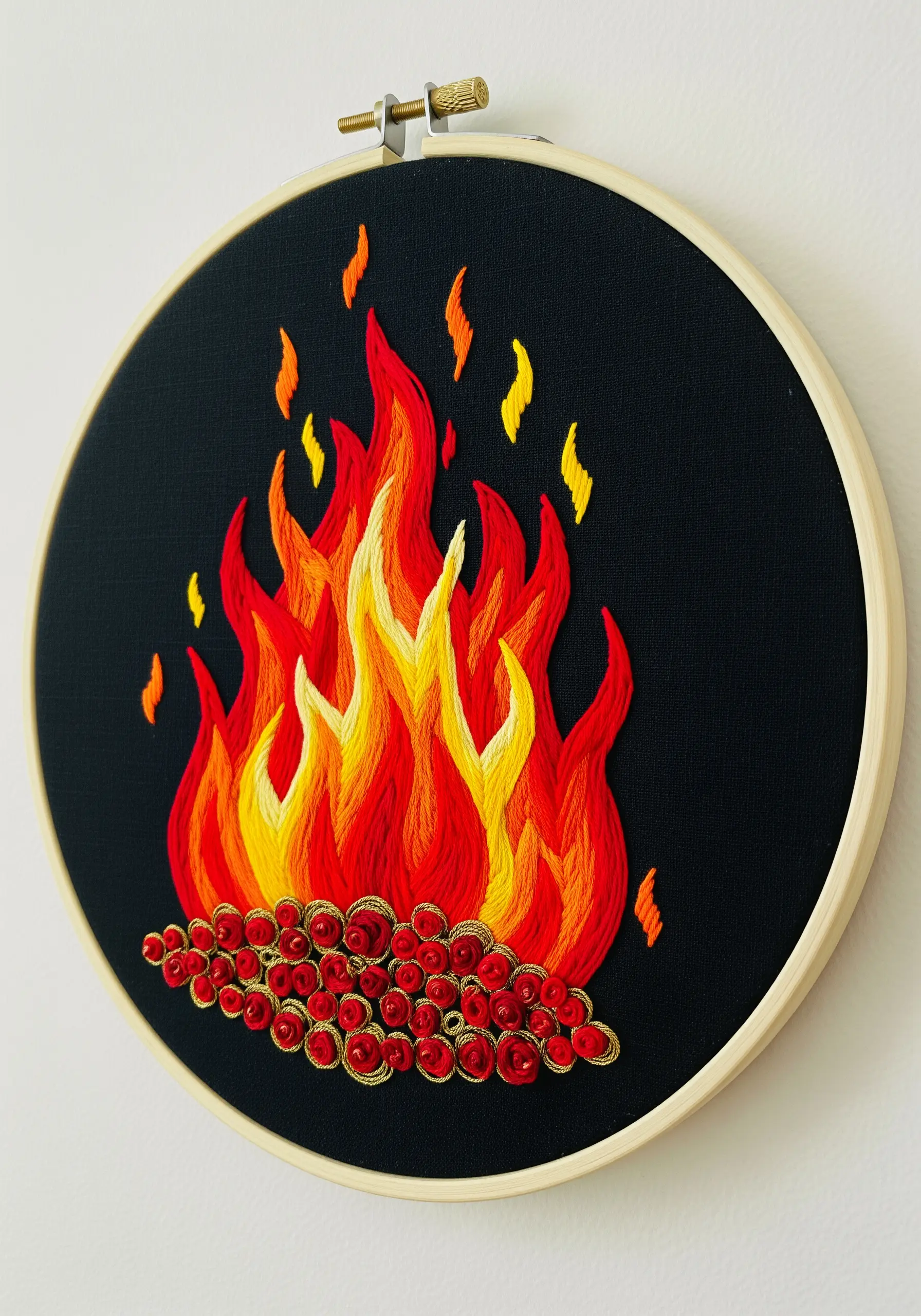 Embroidered fire with red and yellow satin stitch flames and bullion knot embers.