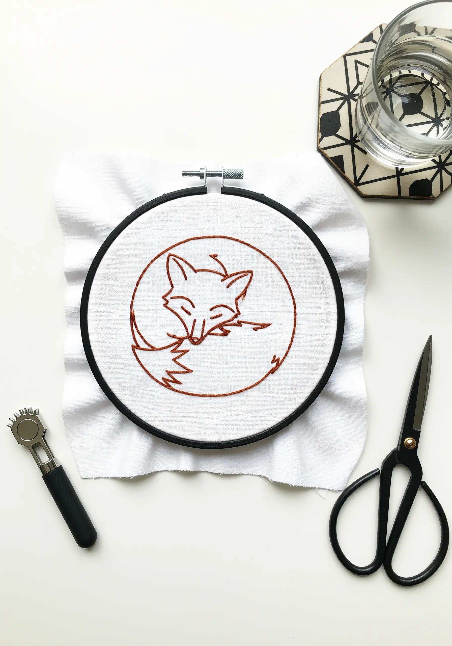 Minimalist line art embroidery of a sleeping fox stitched in rust-colored thread.