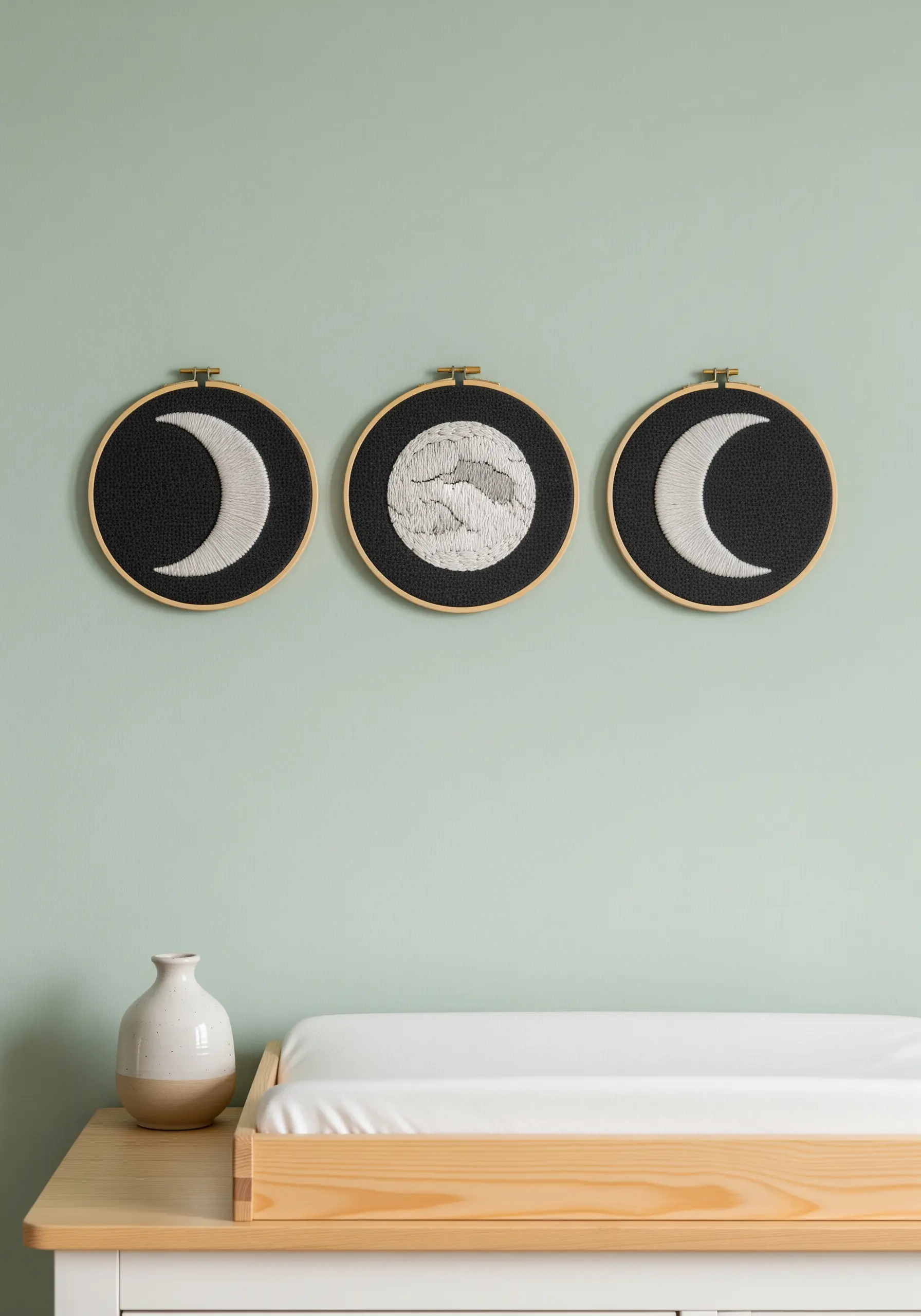 A triptych of moon phase embroideries on black fabric for a nursery wall.