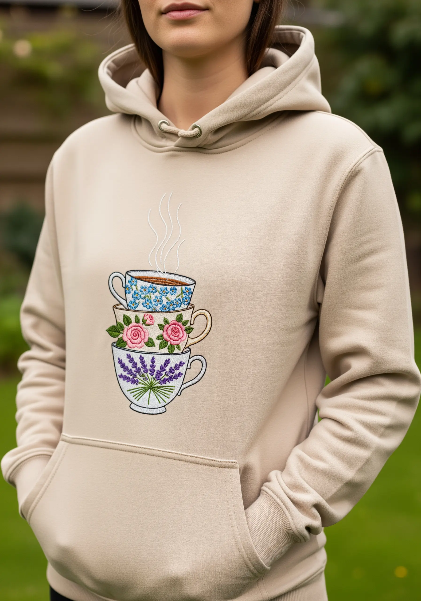 A stack of three teacups, each with a different delicate floral pattern, on a beige hoodie.