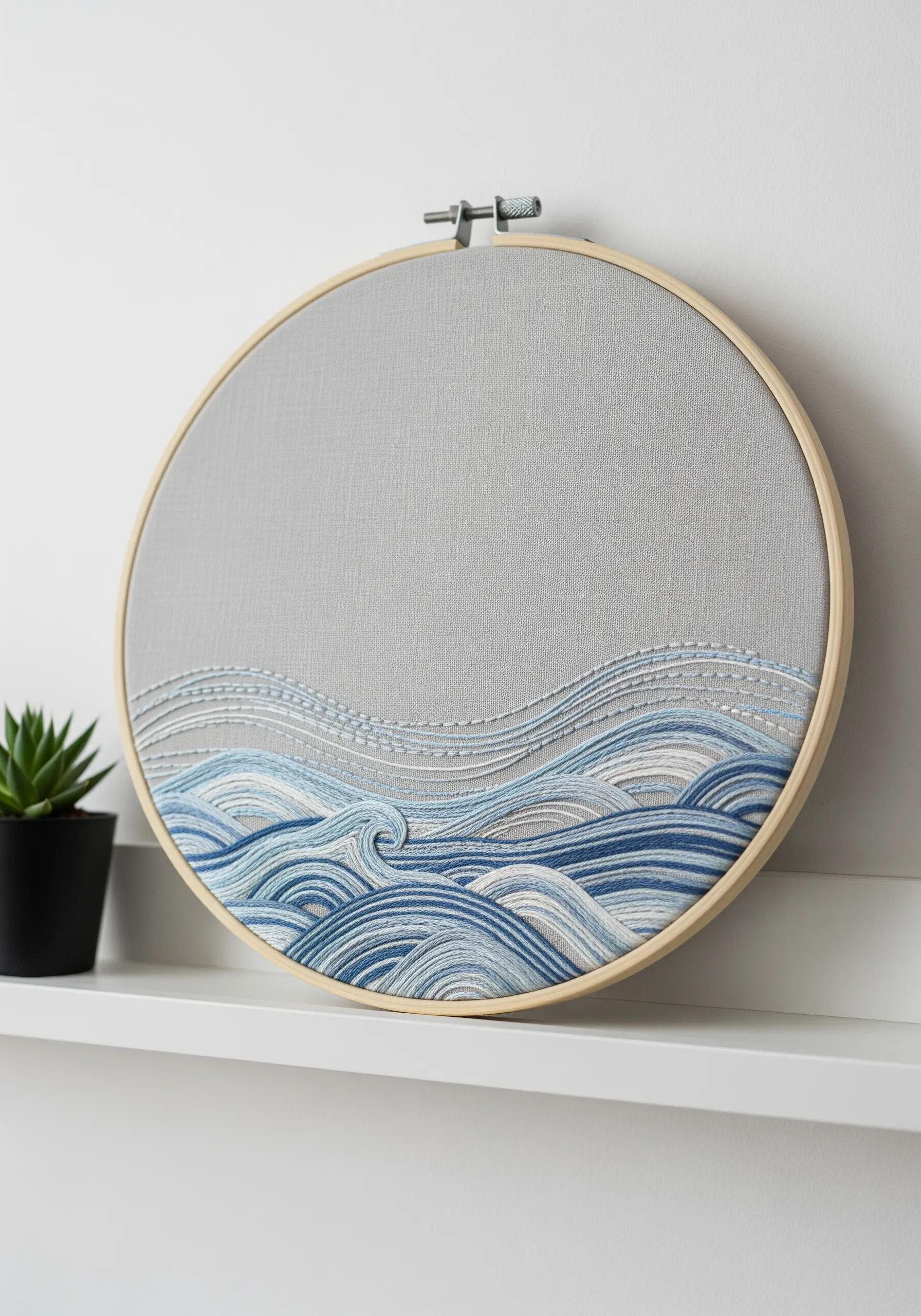 Hoop art embroidery of stylized ocean waves in various shades of blue and white.