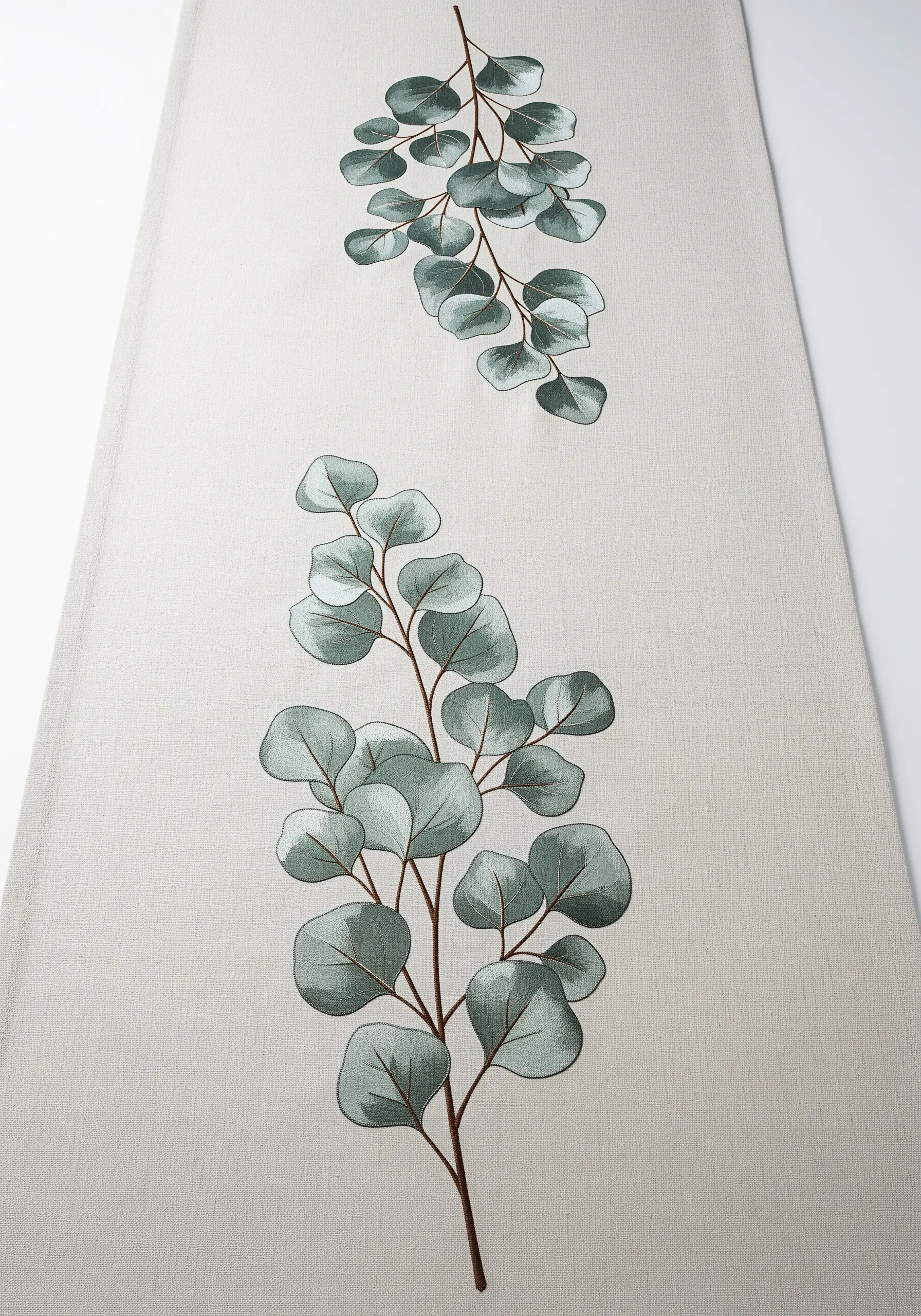 Embroidered eucalyptus branches with soft, blended green leaves on a long table runner.