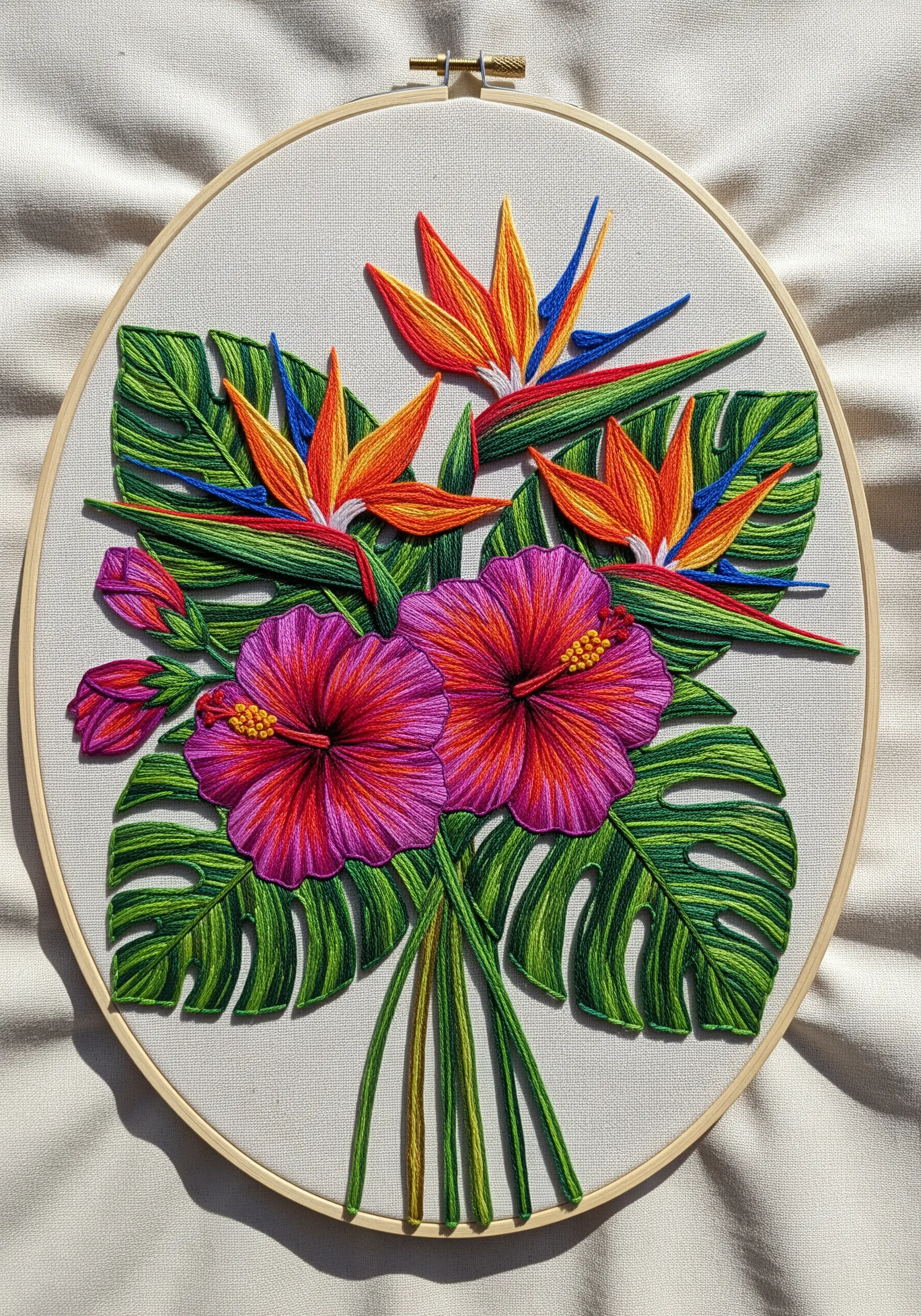 A tropical embroidered bouquet of hibiscus, bird of paradise, and monstera leaves in a hoop.