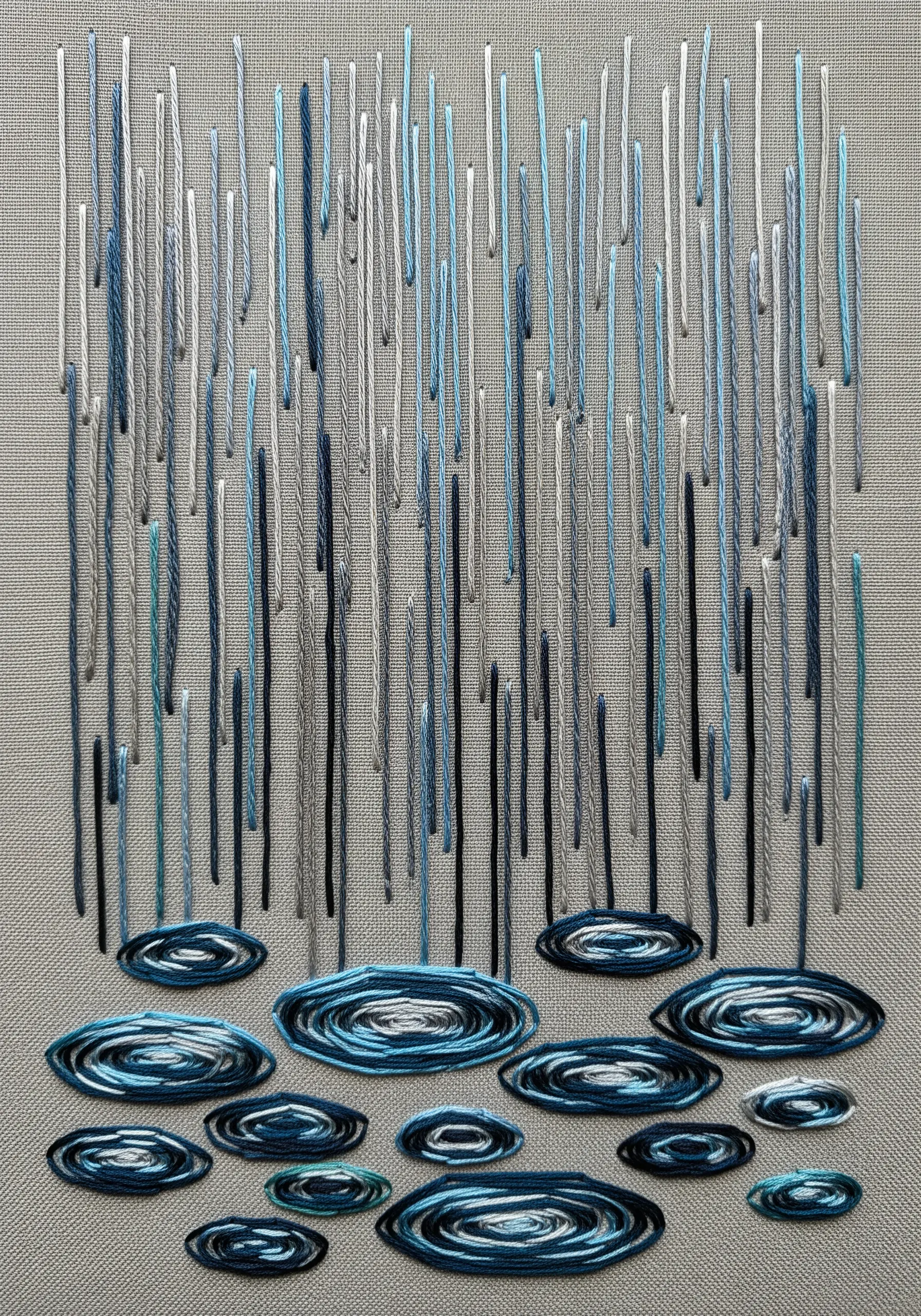 Embroidered rain and puddles using vertical straight stitches and concentric ovals.