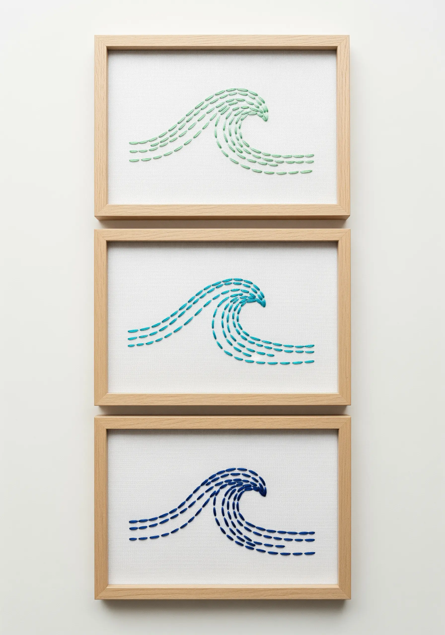Three framed embroideries of waves, each in a different shade of blue-green.
