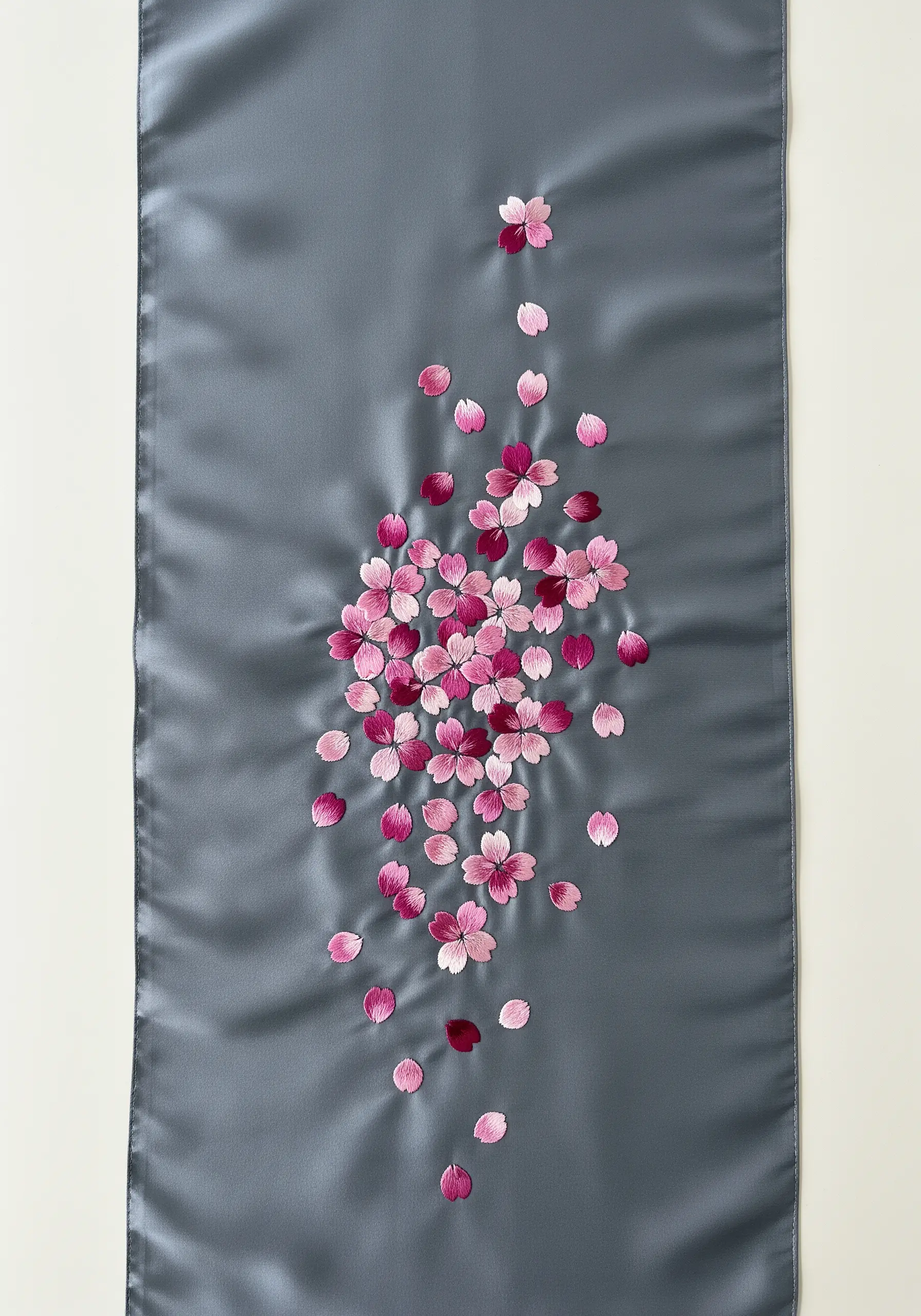 Embroidered cherry blossom petals cascading down a gray satin table runner.