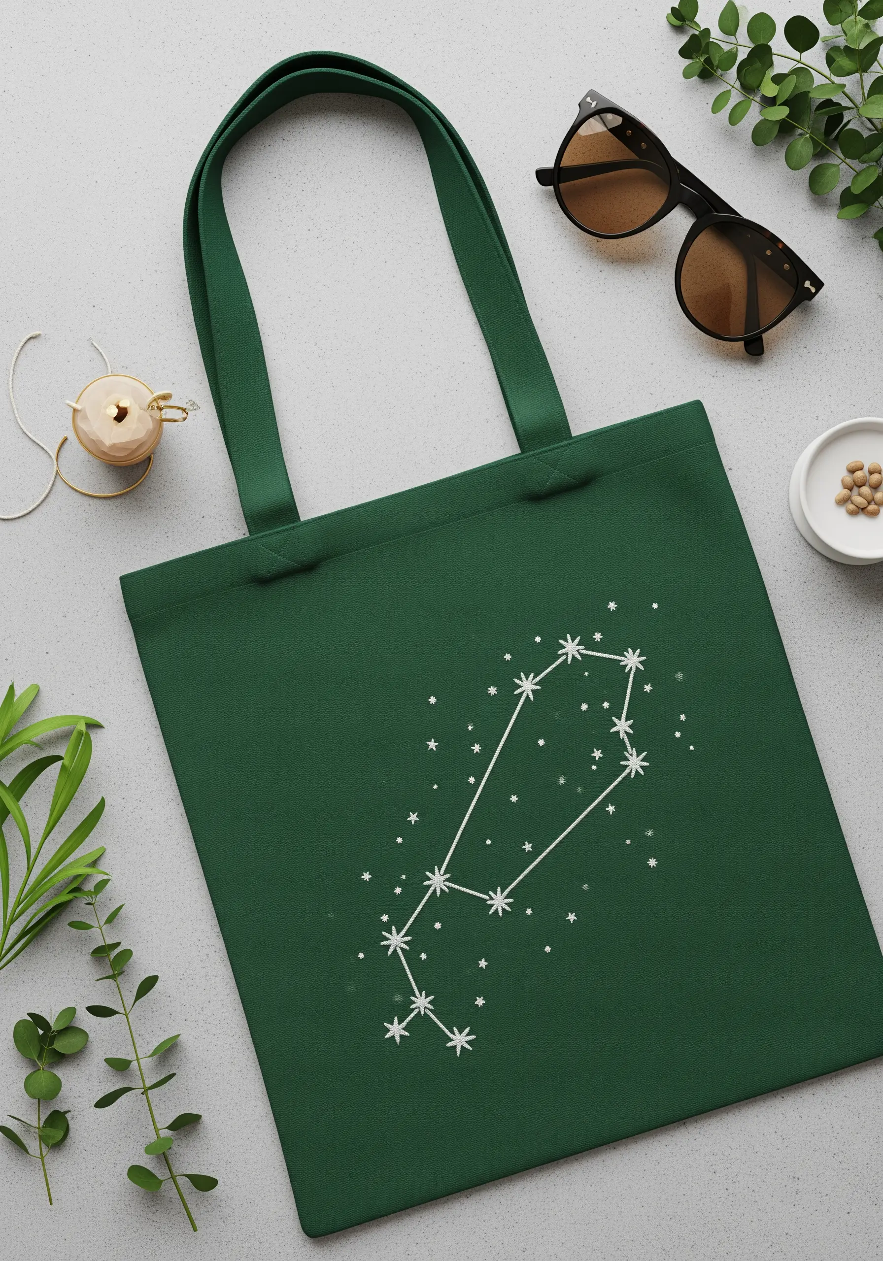 A constellation pattern stitched in white thread on a dark green tote bag.